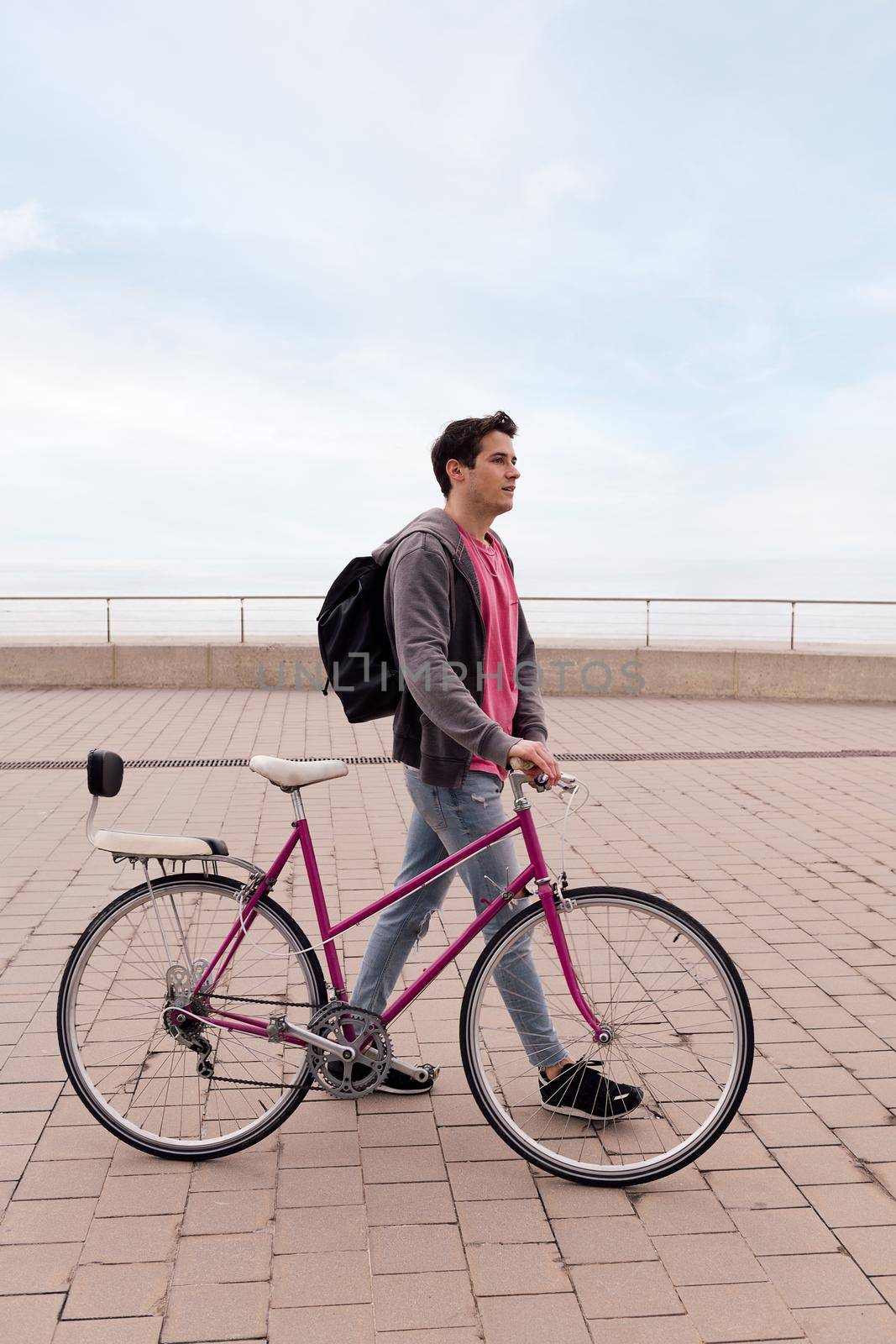 vertical photo of a stylish young man walking with a vintage bike, concept of sustainable transportation and urban lifestyle, copy space for text