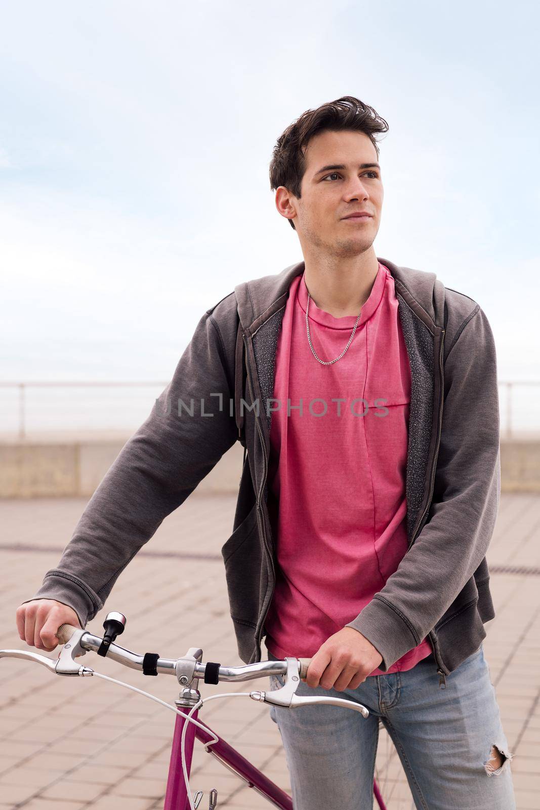 vertical portrait of a handsome young man walking with a vintage bike, concept of sustainable transportation and urban lifestyle