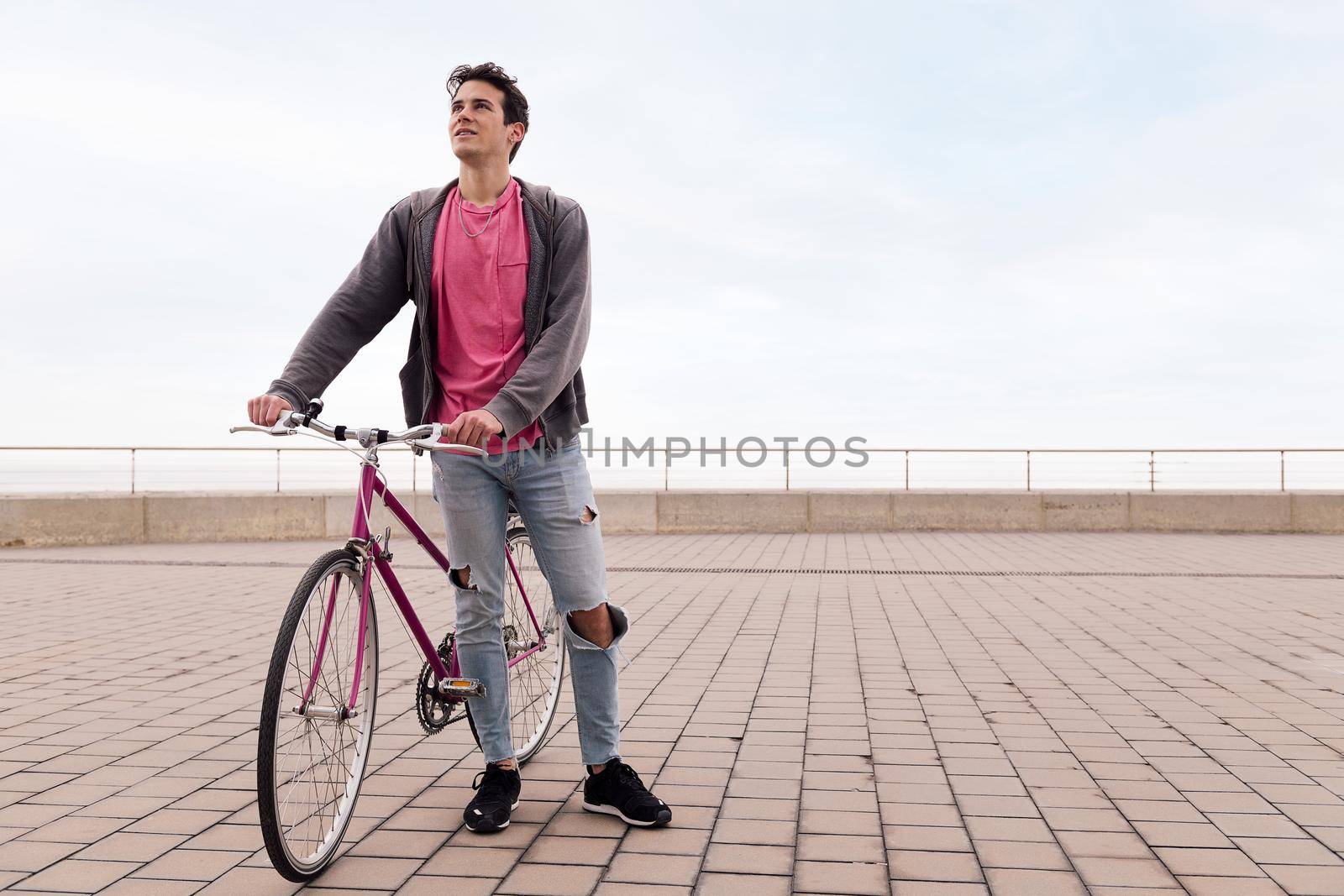 handsome young student holding a vintage bike, concept of sustainable transportation and urban lifestyle, copy space for text