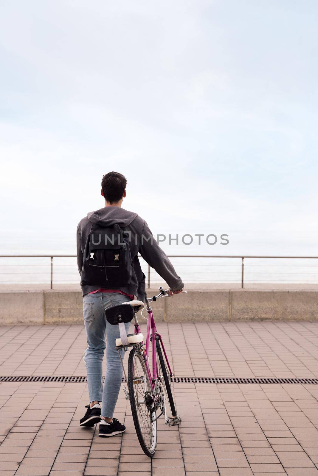 rear view of a young man walking with a bicycle by raulmelldo