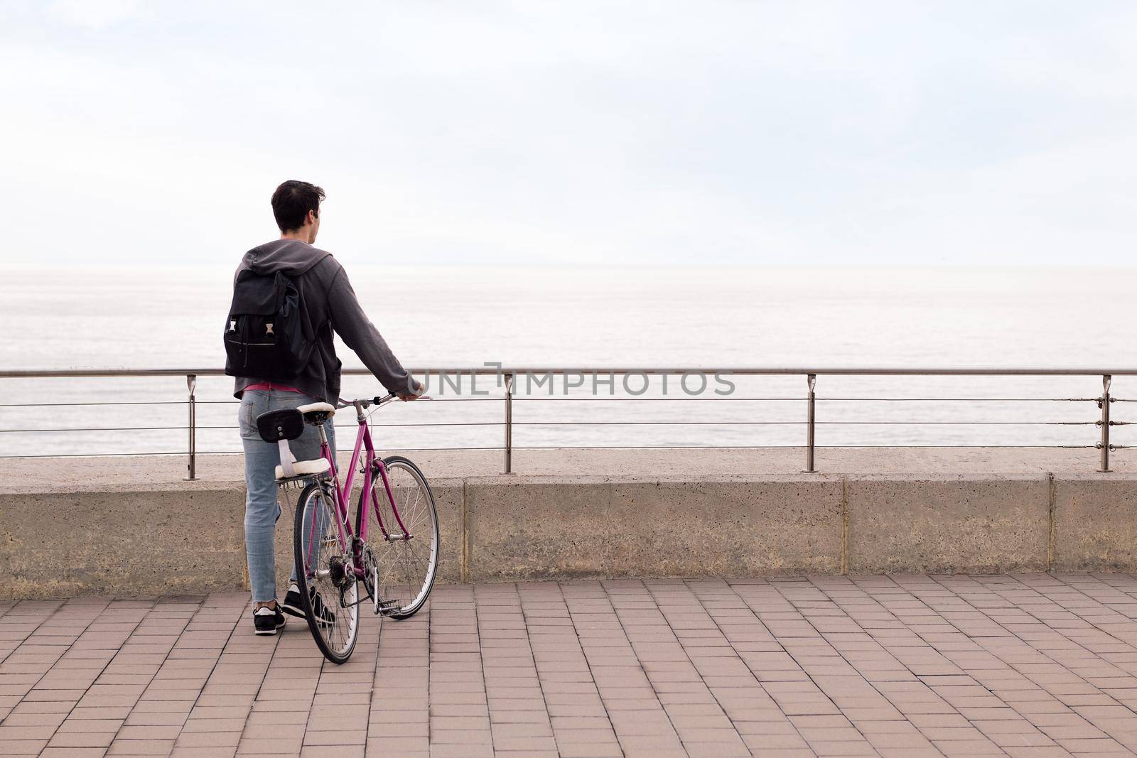 rear view of a young man walking with a bicycle, concept of sustainable transportation and urban lifestyle, copy space for text