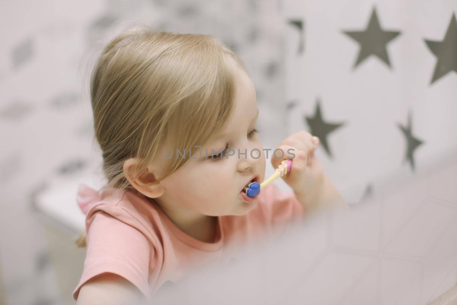 Cute toddler girl brushing teeth in the bathroom. Teeth cleaning, dental care. by paralisart