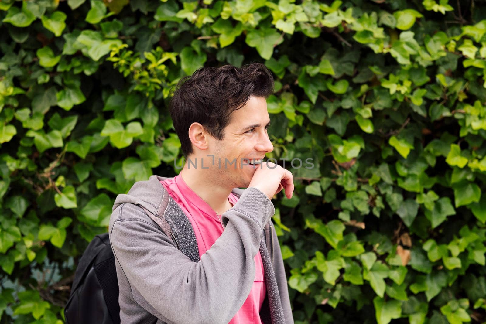 friendly young man laughing on a green plants background, concept of ecology and happiness, copy space for text