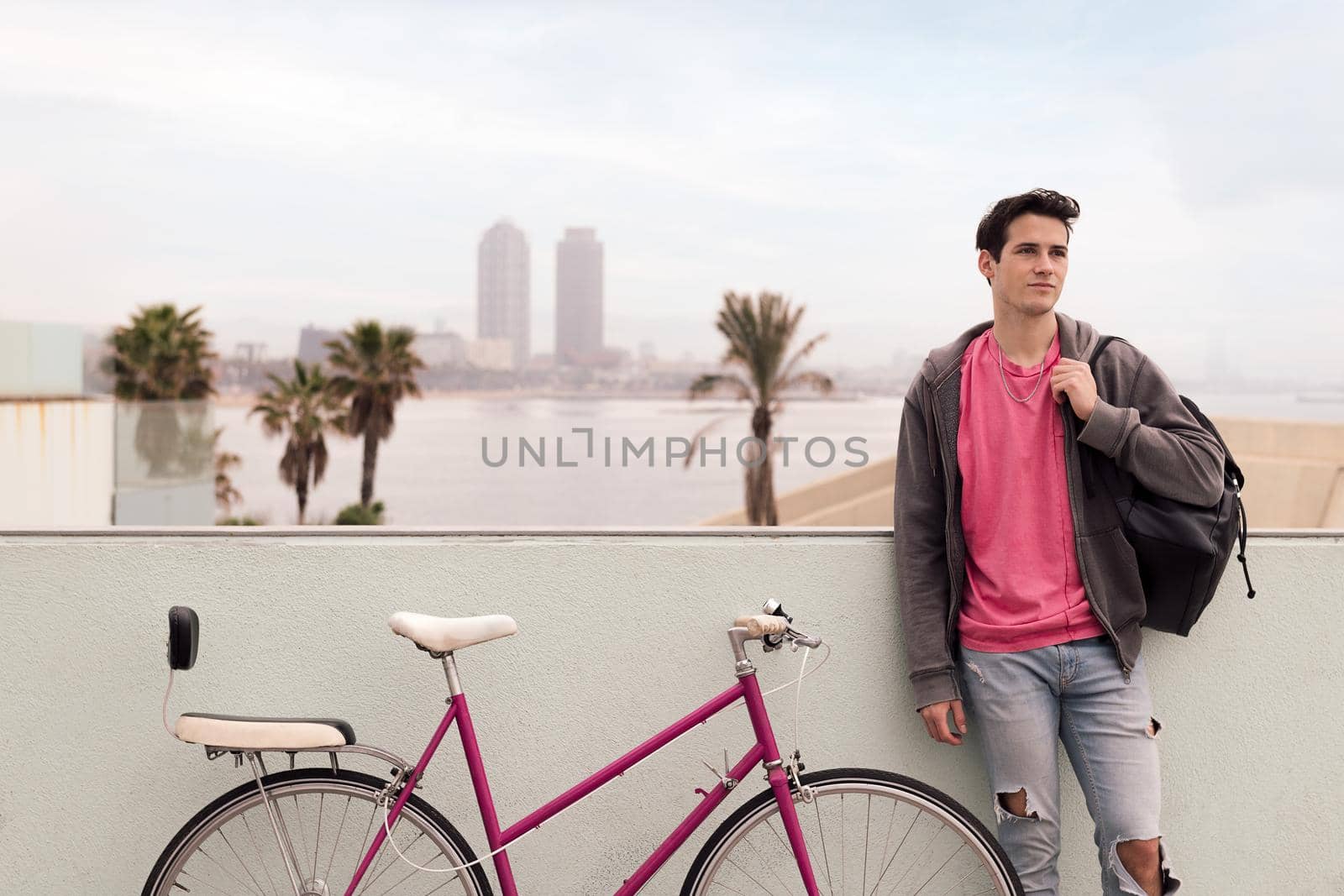 stylish young urban man in front of the city with his vintage bicycle, concept of youth and active lifestyle, copy space for text
