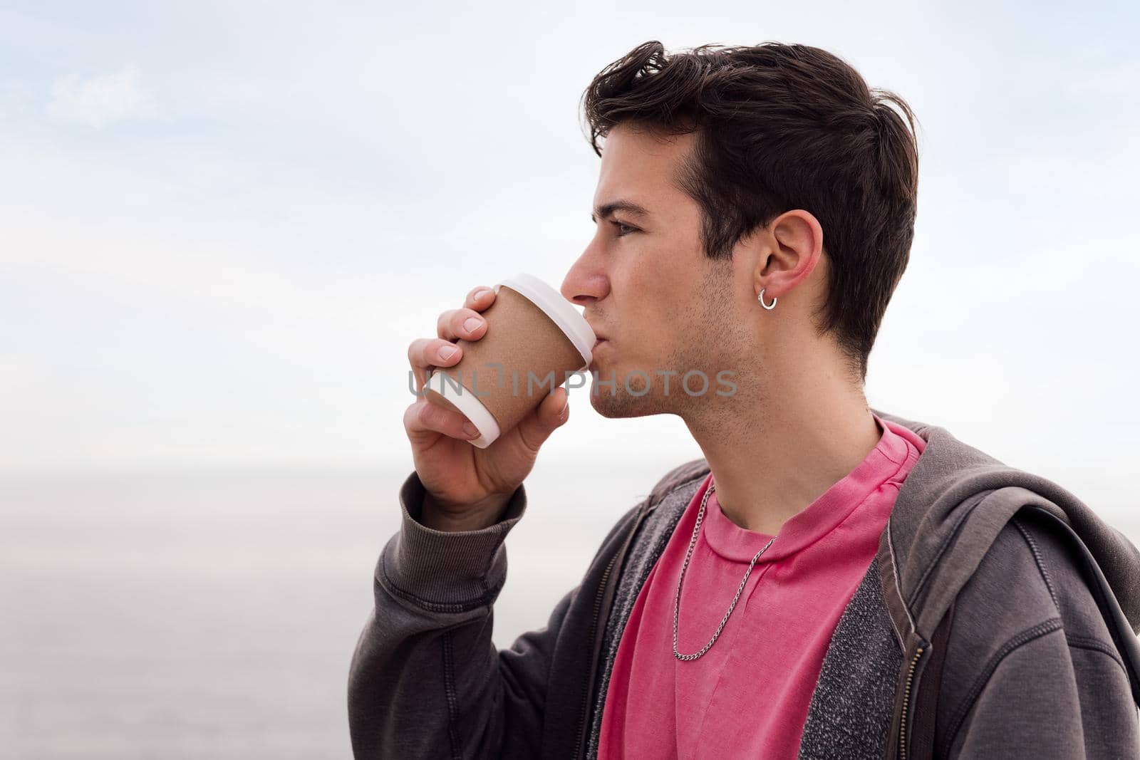 portrait of a handsome young man drinking a cup of coffee outdoors, concept of urban lifestyle, copy space for text