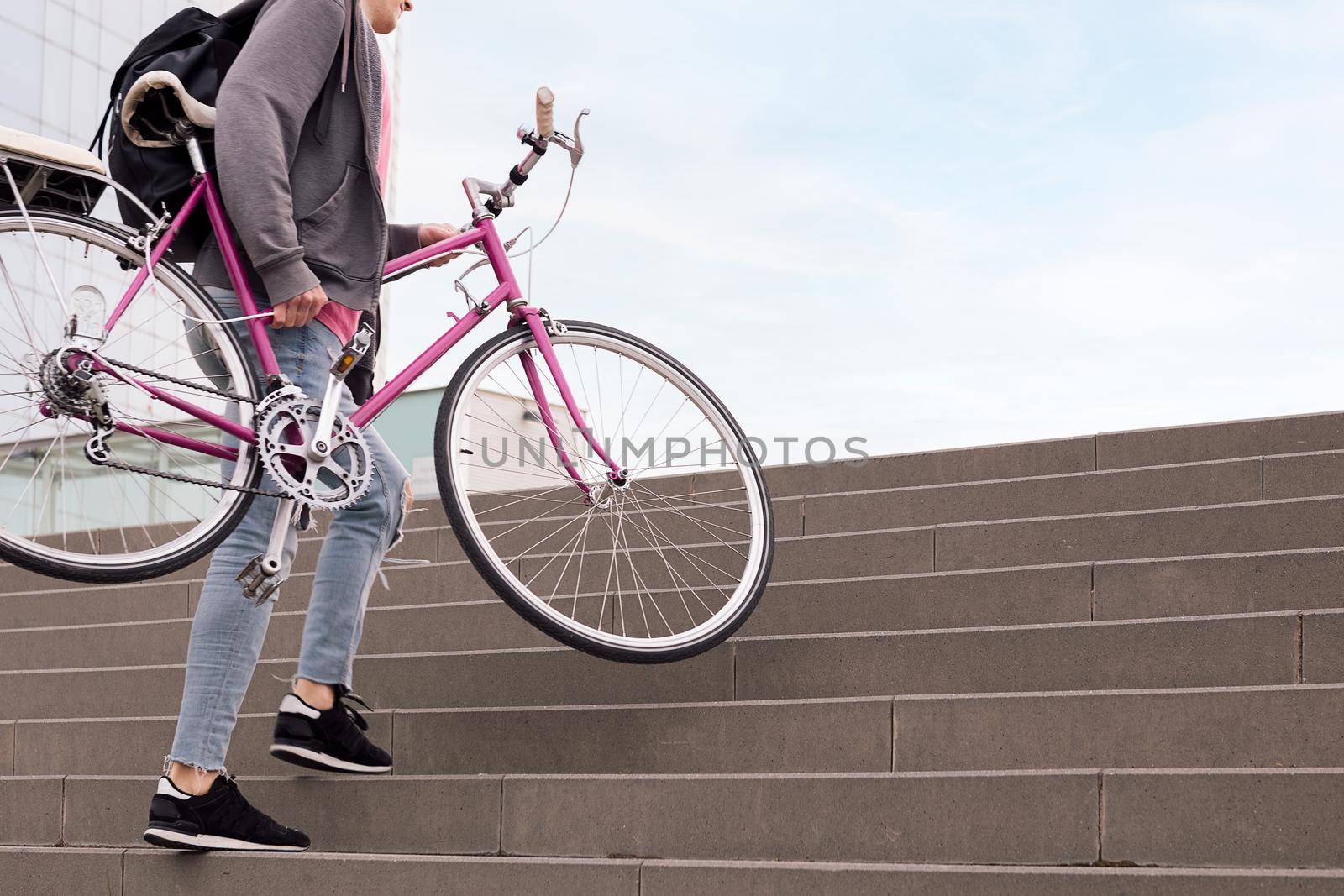 unrecognizable young man carrying bicycle up the stairs, concept of sustainable urban transportation and ecological lifestyle, copy space for text