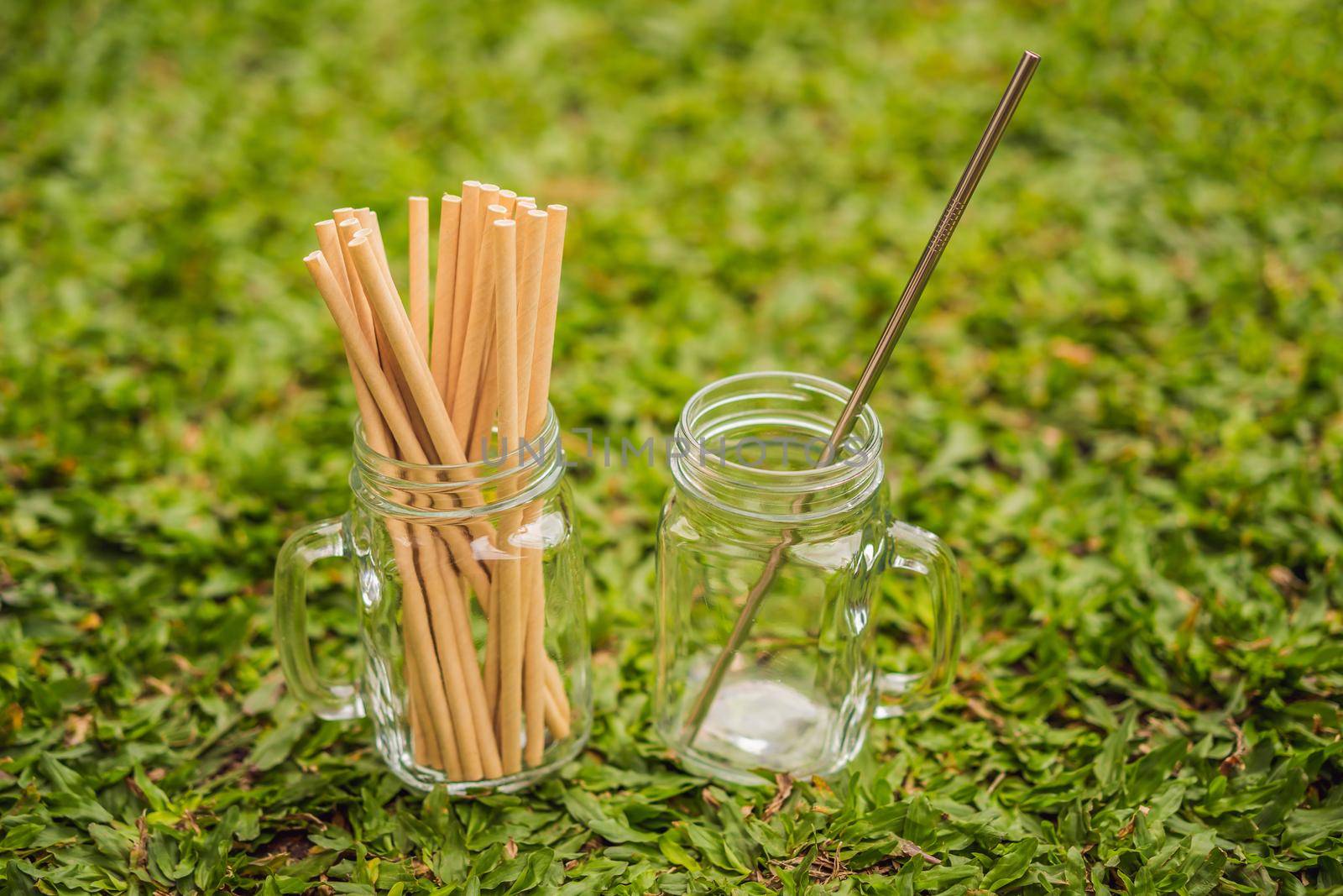 Steel drinking vs disposable straws on grass background. Zero waste concept.