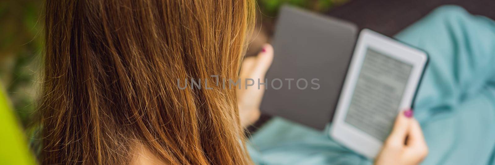 Woman reads e-book on deck chair in the garden. BANNER, LONG FORMAT