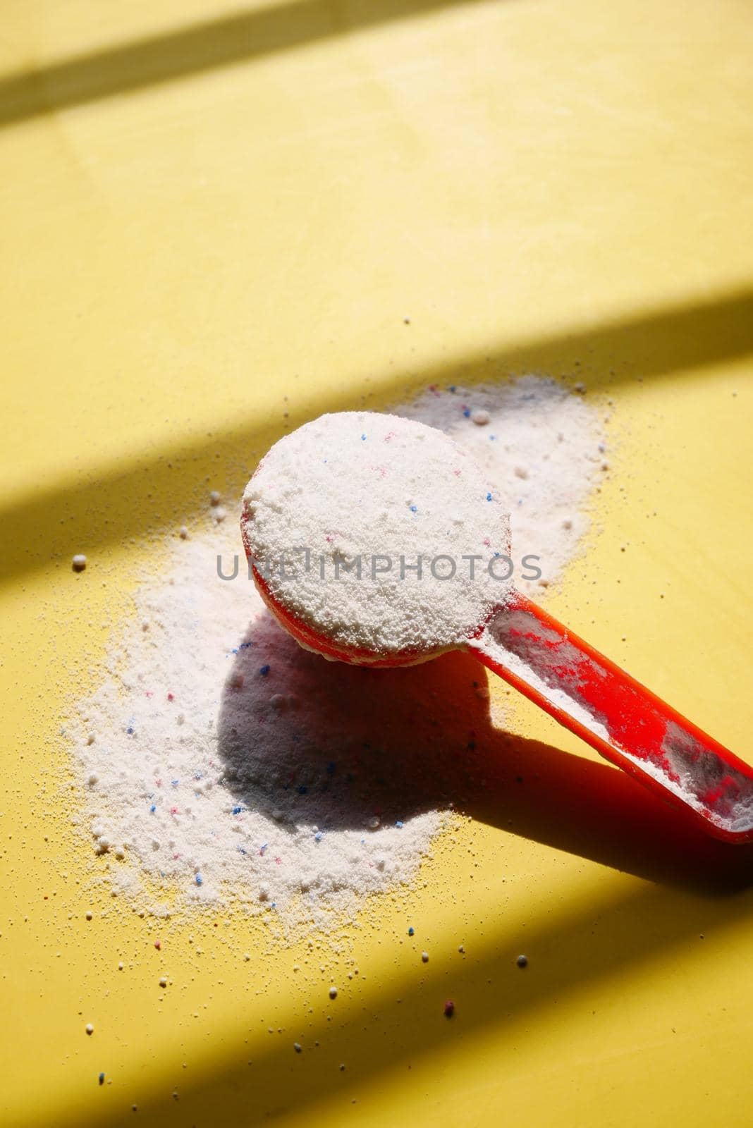 Washing powder in plastic spoon on blue background ,