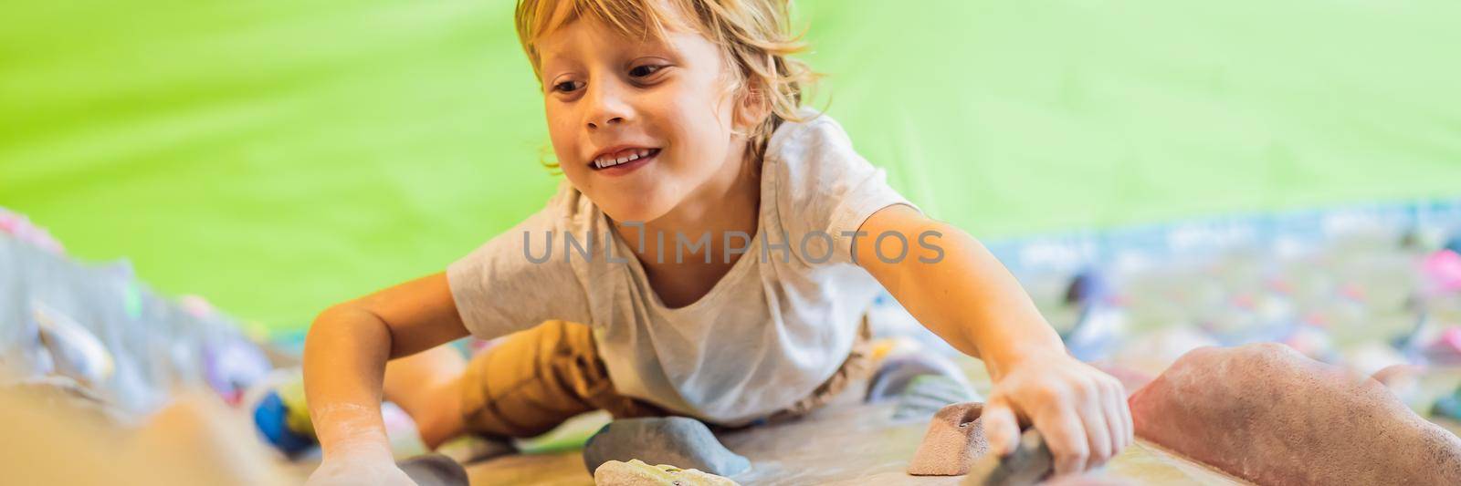 little boy climbing a rock wall in special boots. indoor. BANNER, LONG FORMAT
