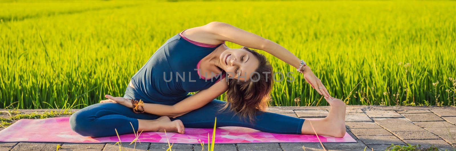 Young woman practice yoga outdoor in rice fields in the morning during wellness retreat in Bali BANNER, LONG FORMAT by galitskaya