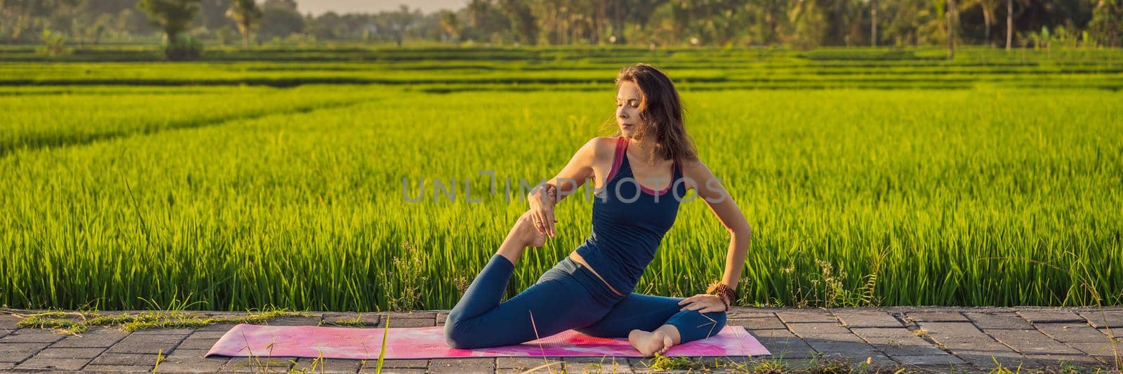 Young woman practice yoga outdoor in rice fields in the morning during wellness retreat in Bali BANNER, LONG FORMAT by galitskaya