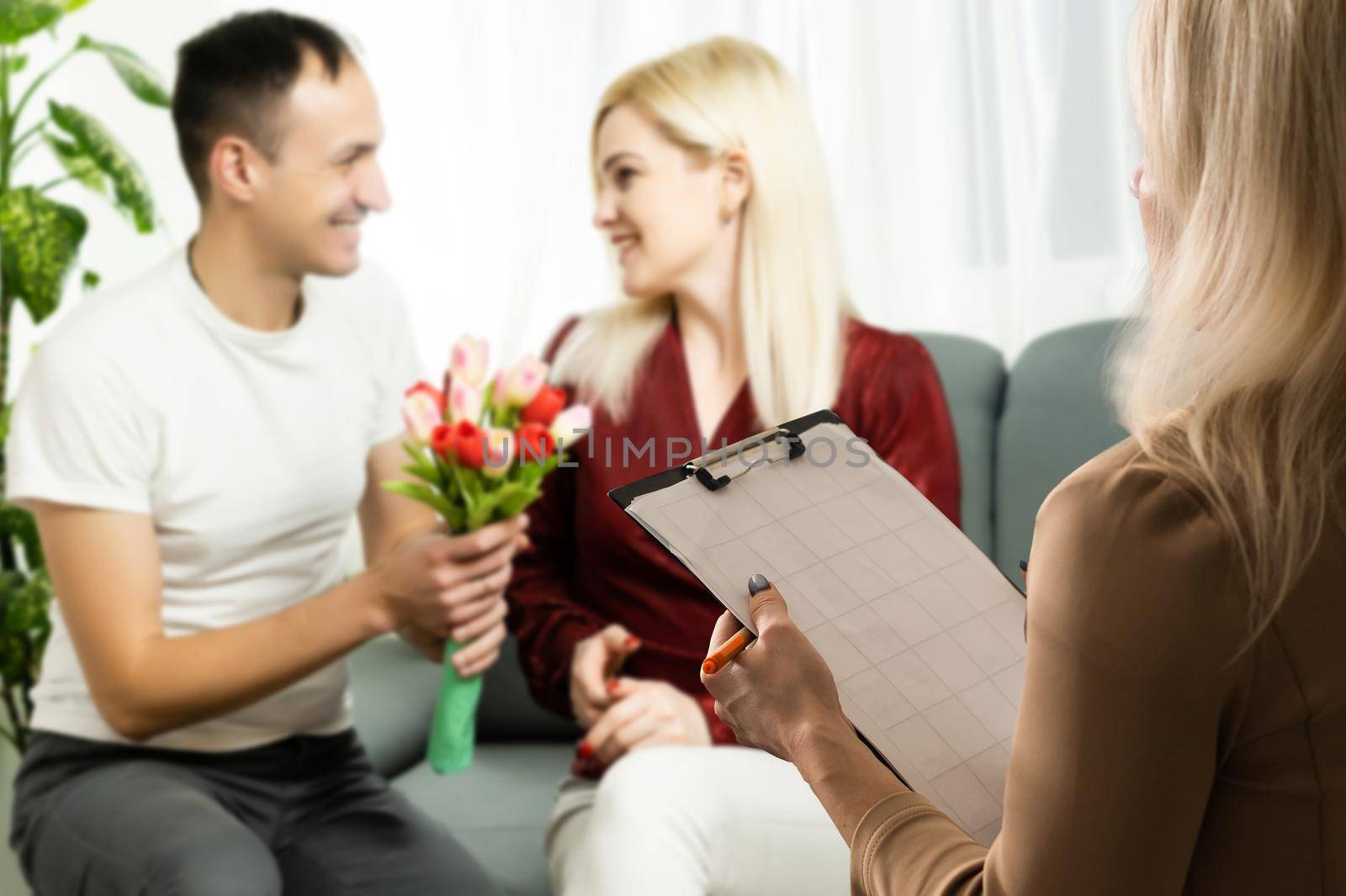 Happy young couple meeting with a broker, view from behind the female agent.
