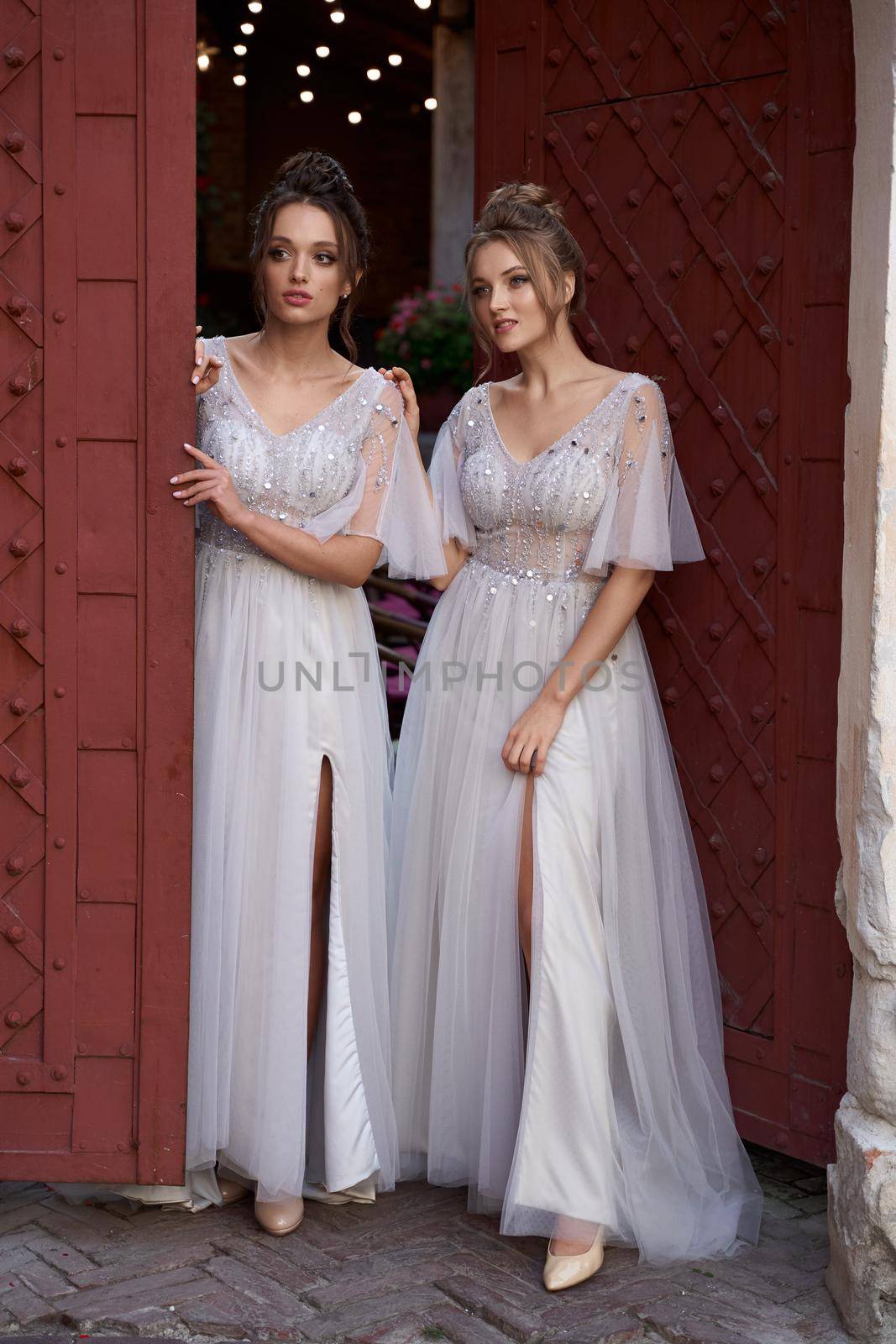 Beautiful bridesmaids in gorgeous elegant stylish silver dress decorated with sequins sparkles. Wedding day in old beautiful European city.