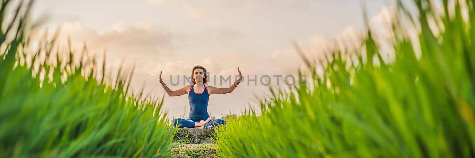 Young woman practice yoga outdoor in rice fields in the morning during wellness retreat in Bali. BANNER, LONG FORMAT