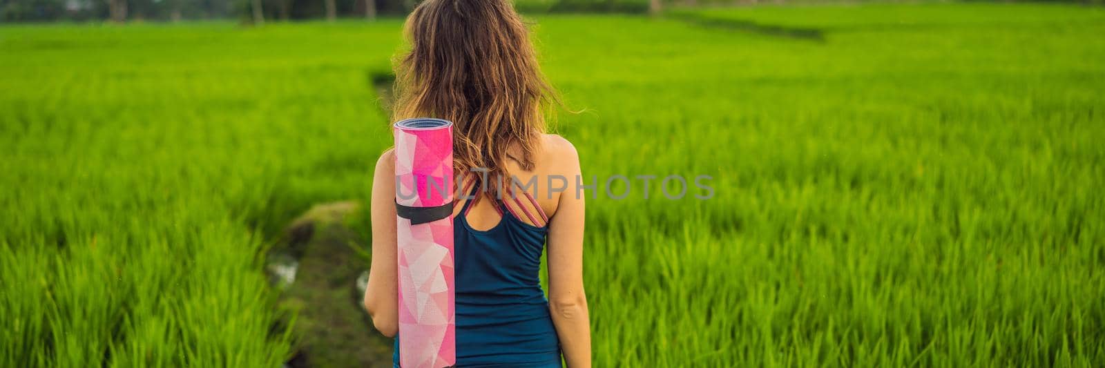 Young woman practice yoga outdoor in rice fields in the morning during wellness retreat in Bali BANNER, LONG FORMAT by galitskaya