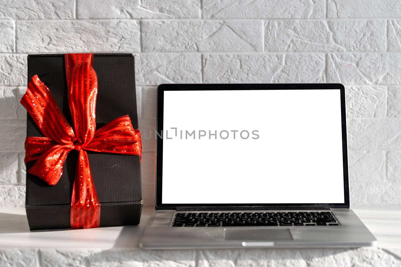 Blank display screen laptop computer on white wood table. Modern cozy comfortable home living room with Christmas decor. Home office desk workspace. Mock up copy space. Winter sales, online shopping