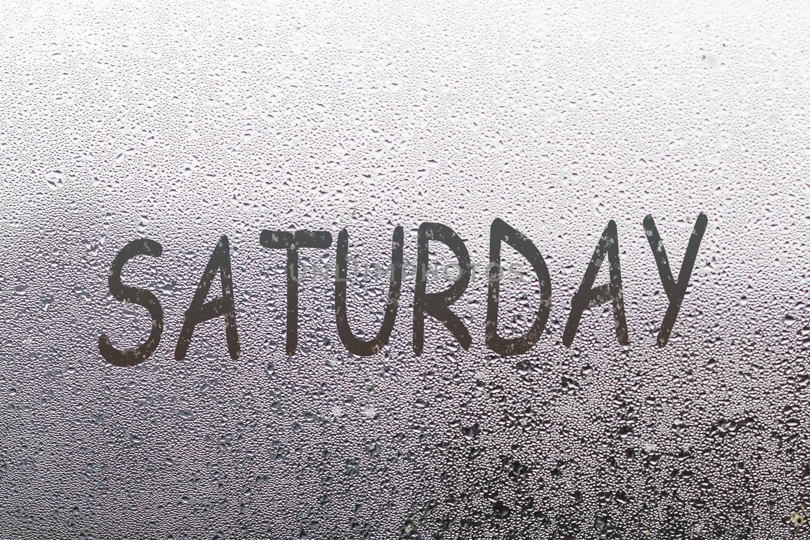 saturday written on the glass screen with raindrops background