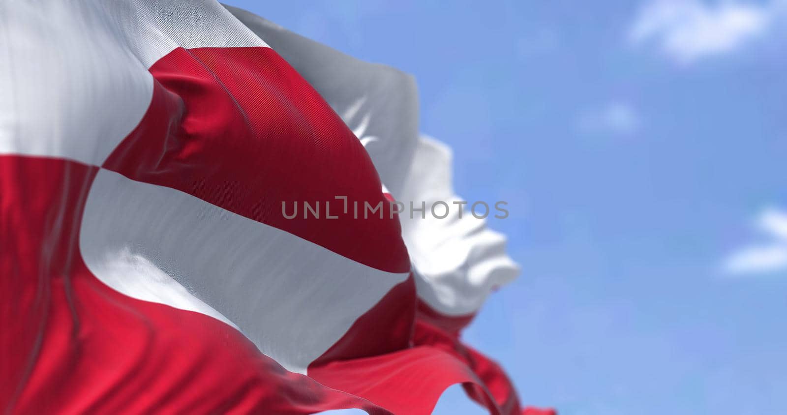 The flag of Greenland waving in the wind on a clear day. Greenland is the world's largest island, and one of the three constituent countries that form the Kingdom of Denmark,