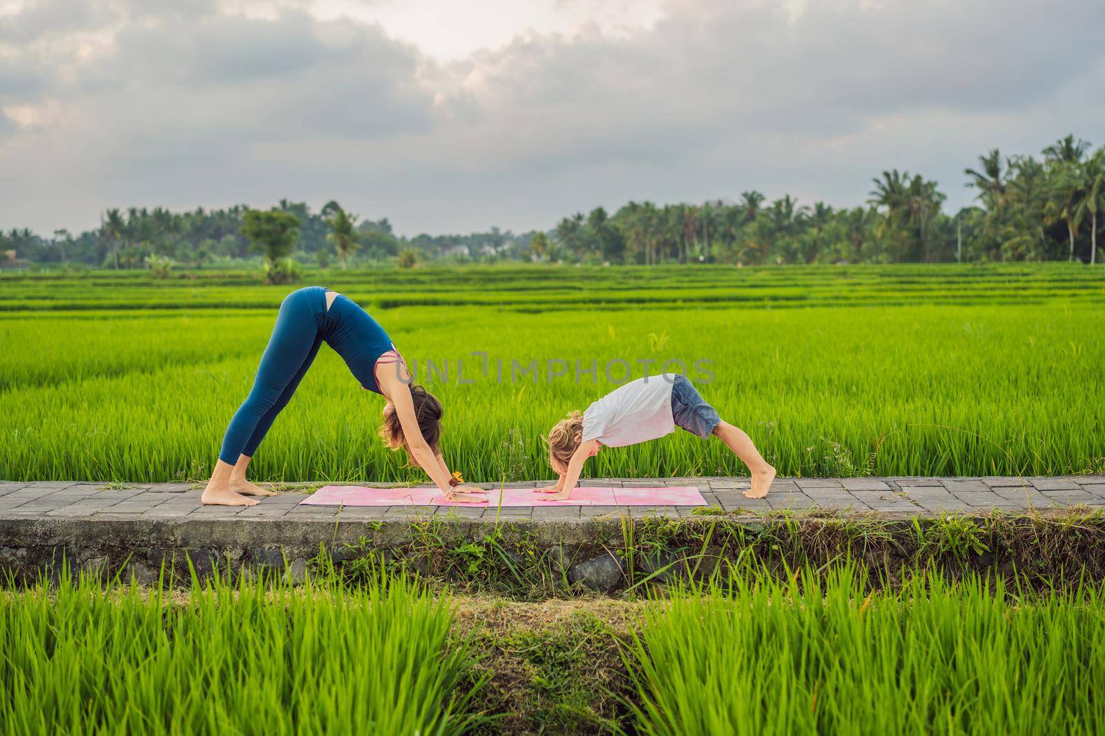 Boy and his yoga teacher doing yoga in a rice field.