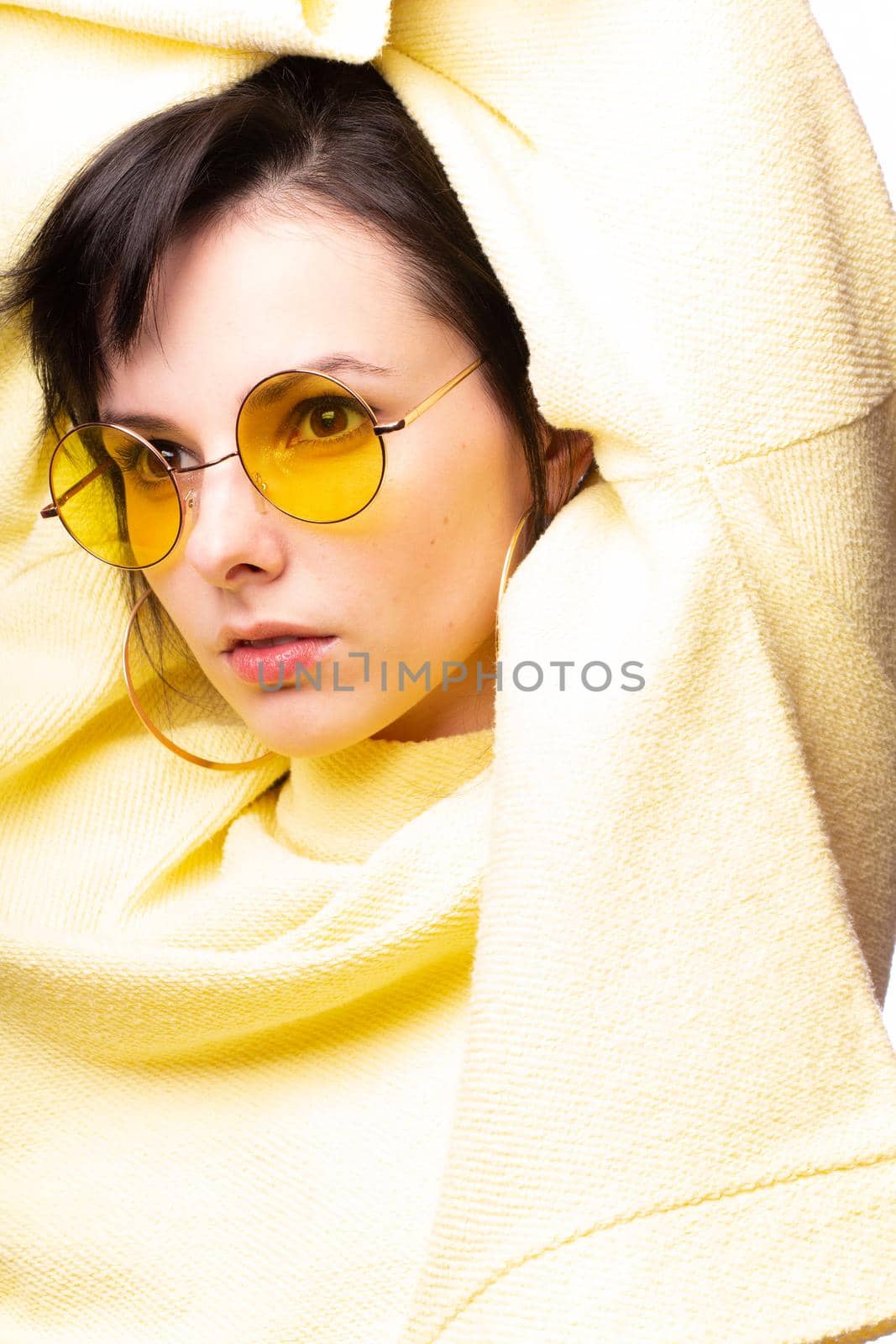 brunette woman in yellow glasses and yellow sweater, close-up portrait, white background by shilovskaya