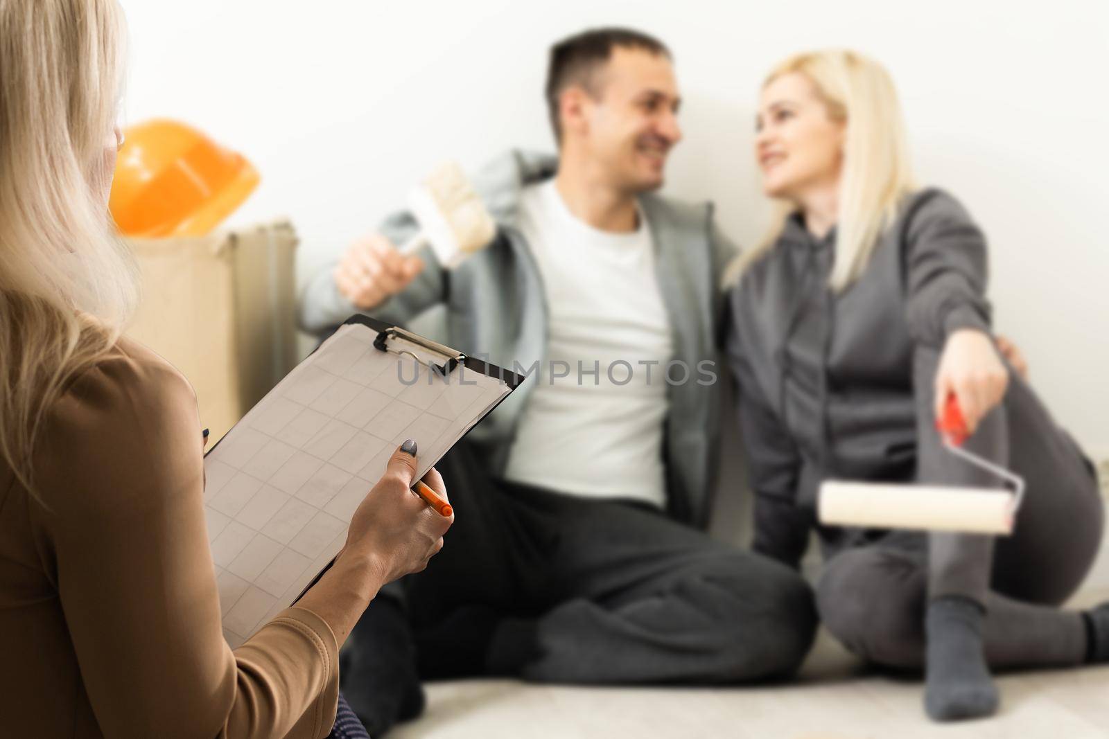 Happy young couple meeting with a broker, view from behind the female agent.