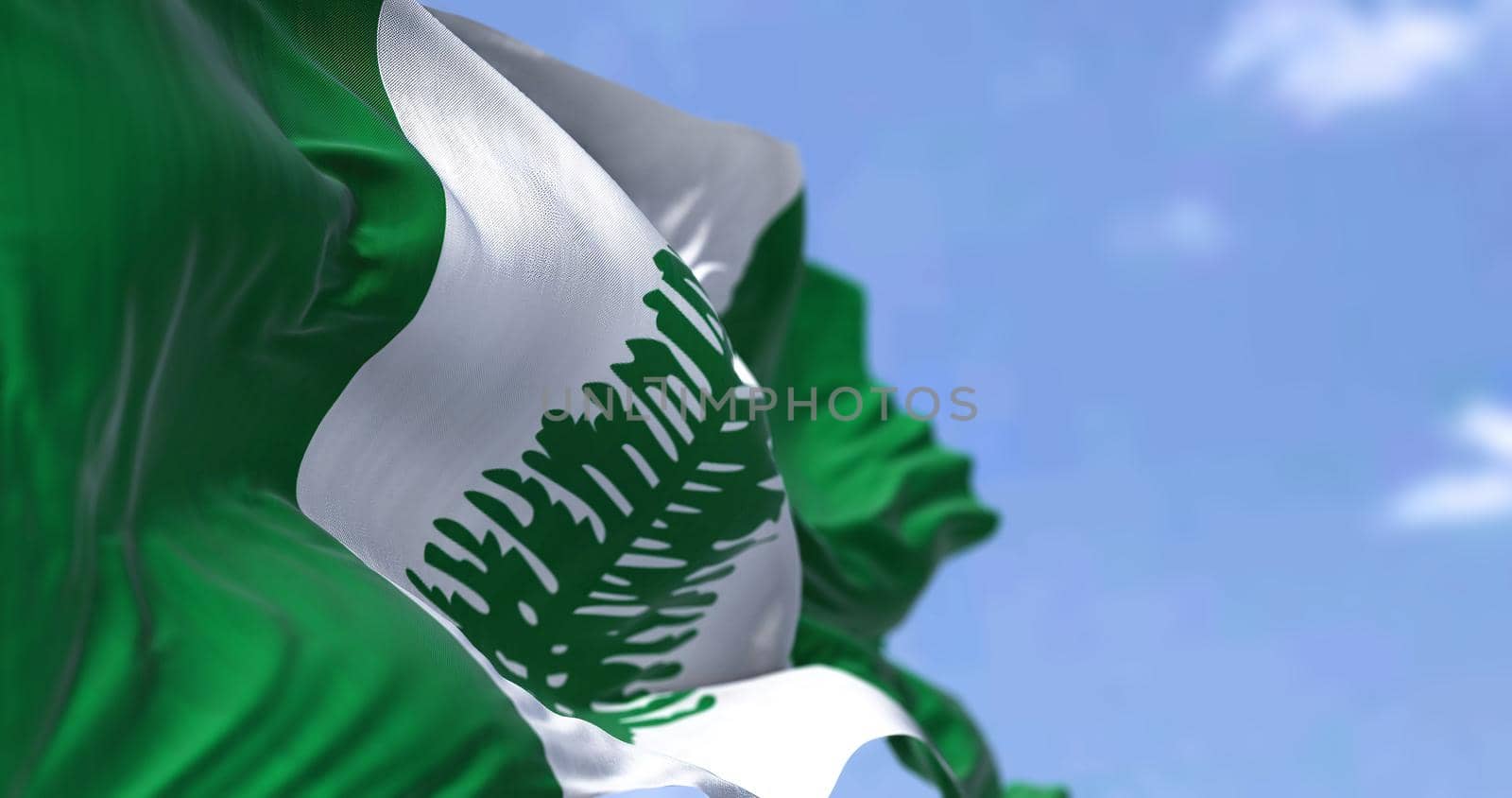 The flag of Norfolk Island waving in the wind on a clear day. Norfolk Island is an external territory of Australia located in the Pacific Ocean