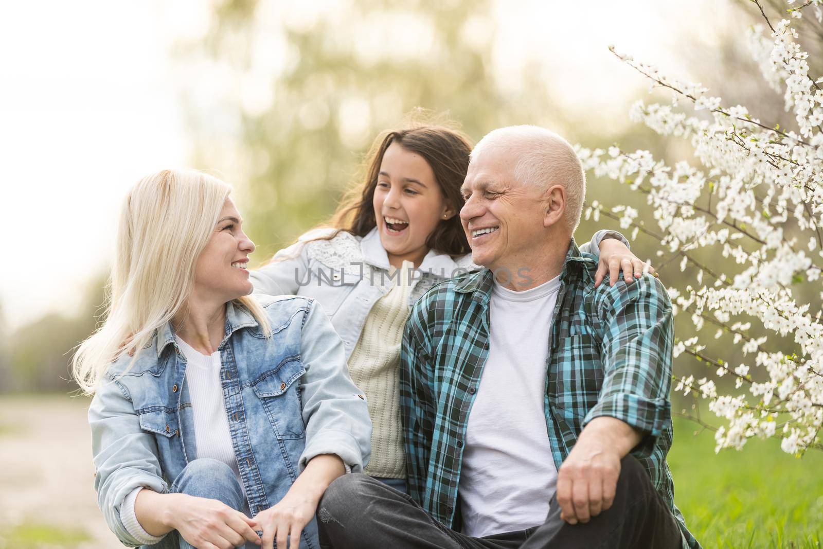 grandfather with granddaughter and daughter in spring, senior man in the yard.