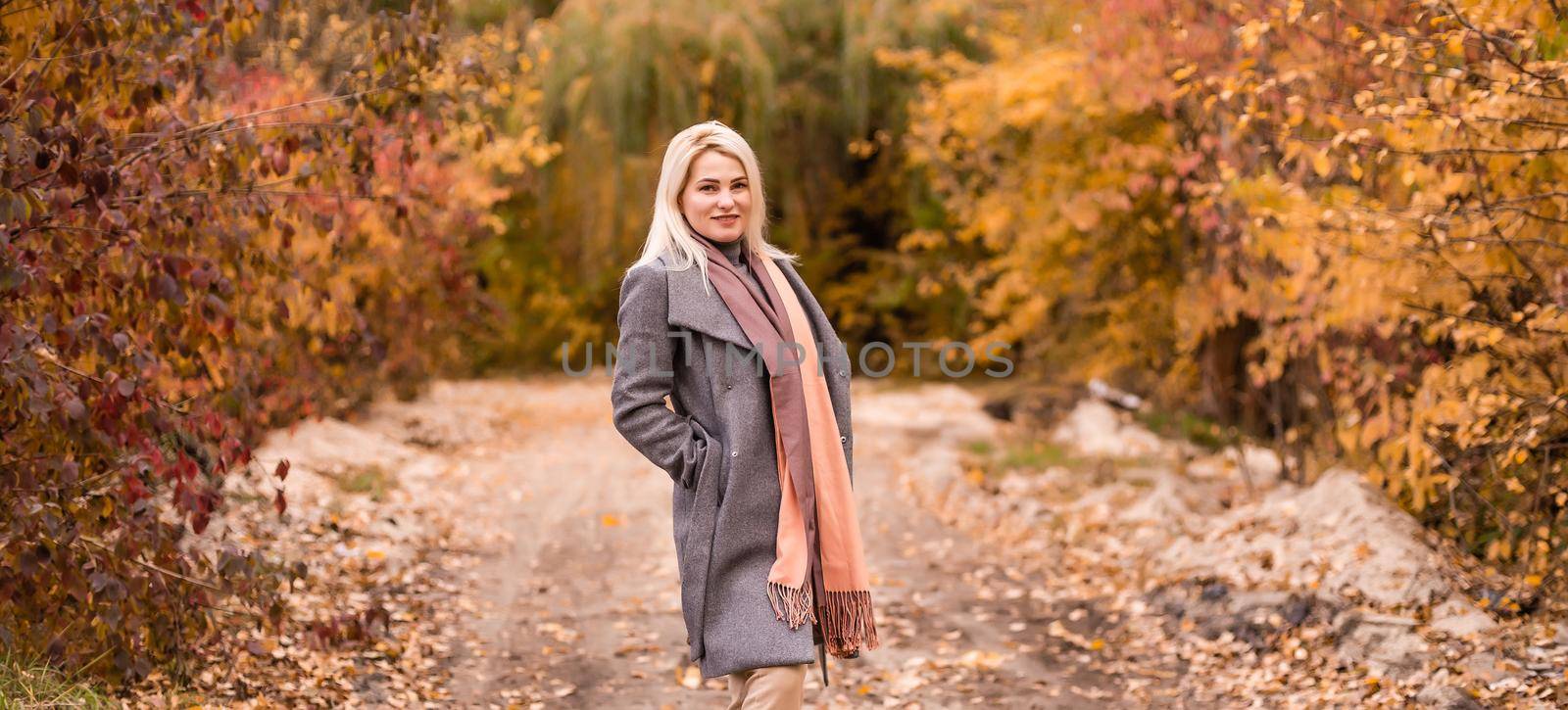 Portrait of beautiful young woman walking outdoors in autumn by Andelov13
