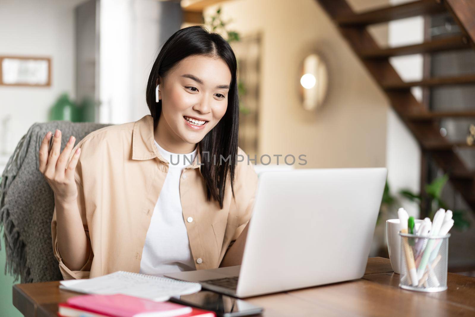 Smiling asian girl talking on laptop, video chatting with friends or students. Young woman tutoring online, teaching lesson via e-learning website.