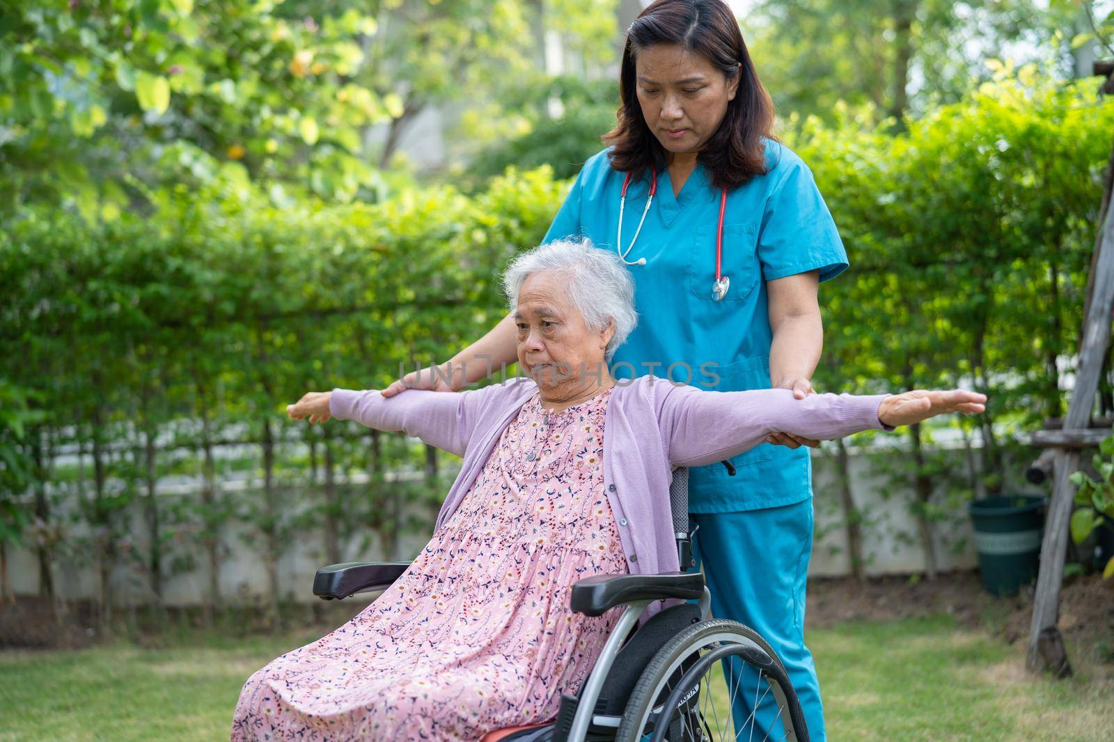 Doctor help Asian senior or elderly old lady woman patient exercise on wheelchair with happy in park. by pamai