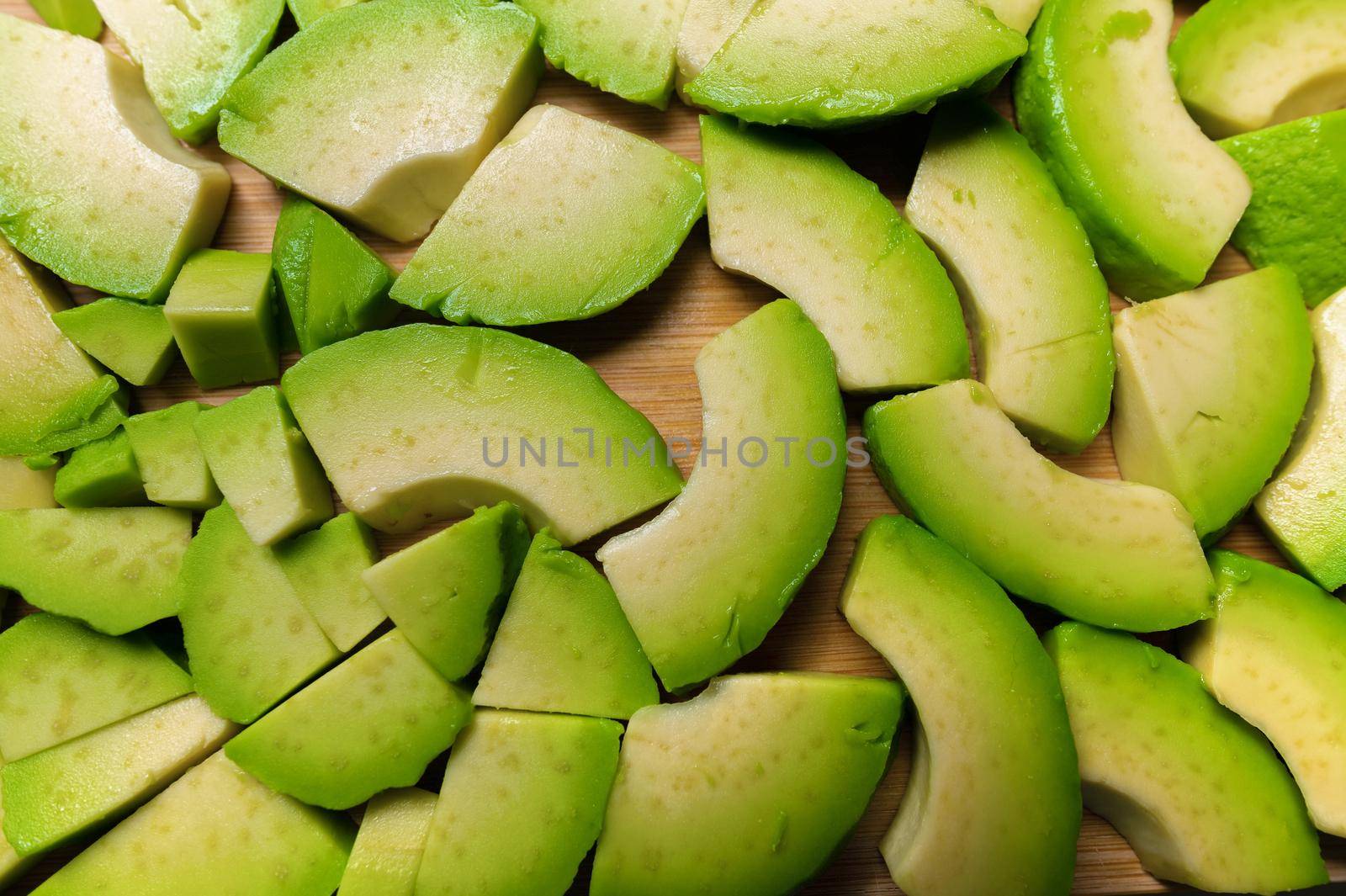 Avocado slices on a wooden board, on a gray table top view