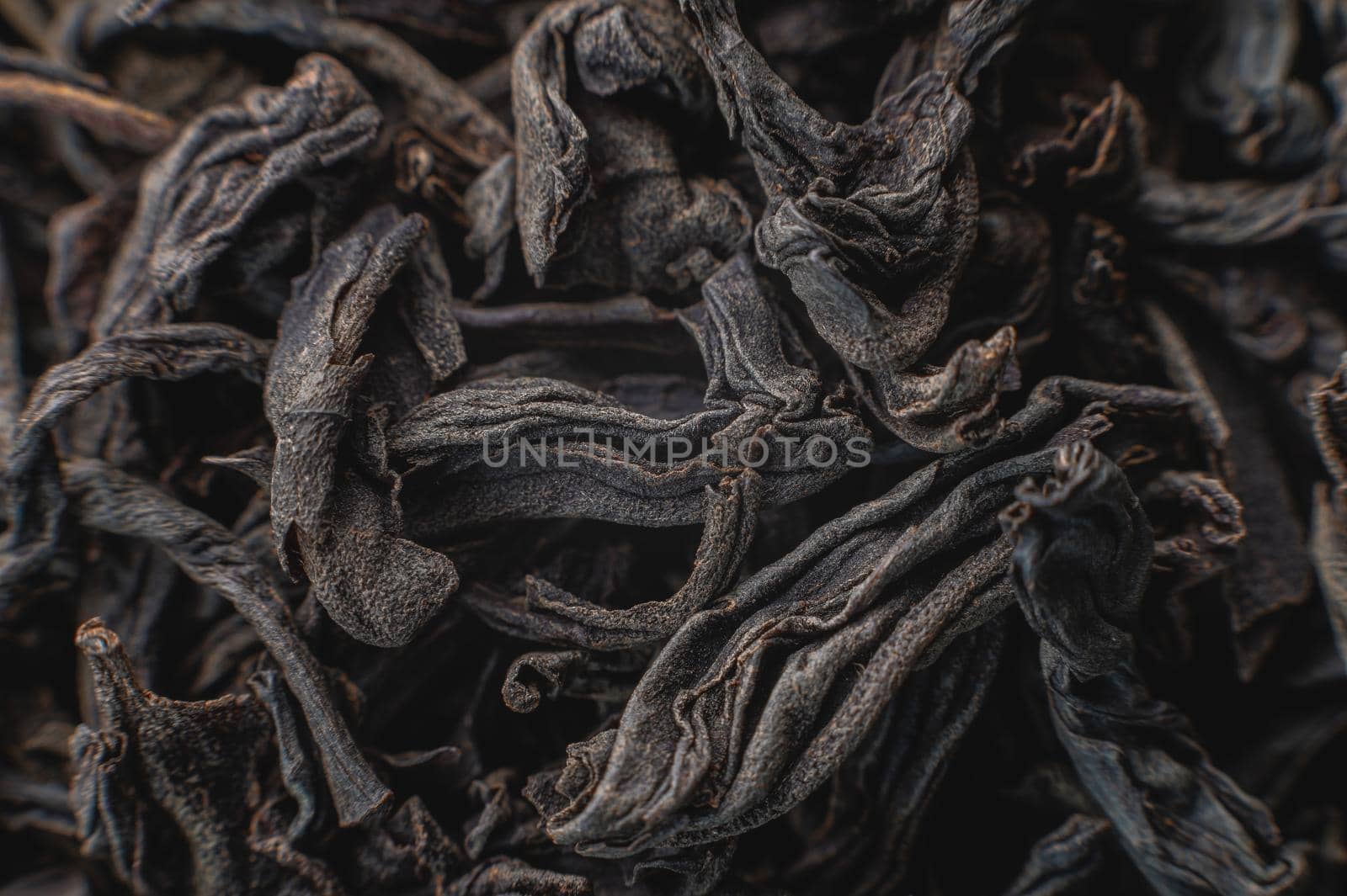 Black loose leaf tea as a background. Texture of dry black tea leaves. Dark background. Extreme macro mode. black leaf tea closeup by yanik88