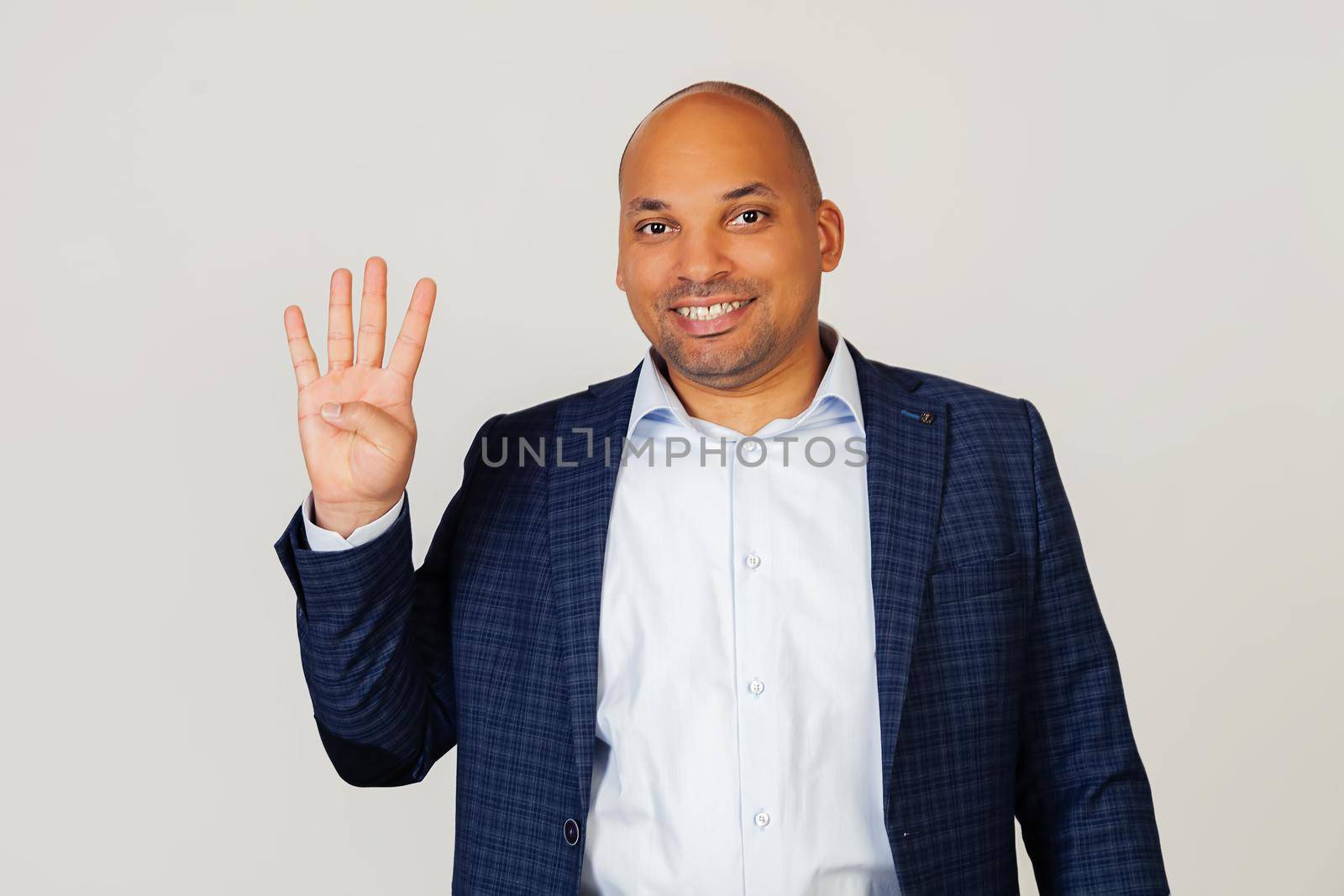 Portrait of a successful young African American businessman guy, showing with fingers to number four, smiling, confident and happy. The man shows four fingers. Number 4. Standing on a gray background