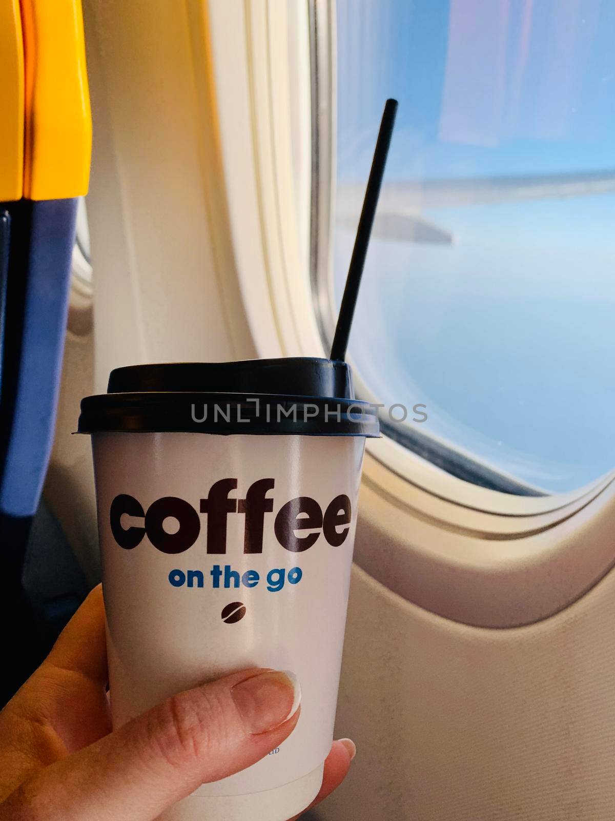 Woman drinking coffee on airplane. Woman hand holding white paper cup of hot coffee on the airplane.