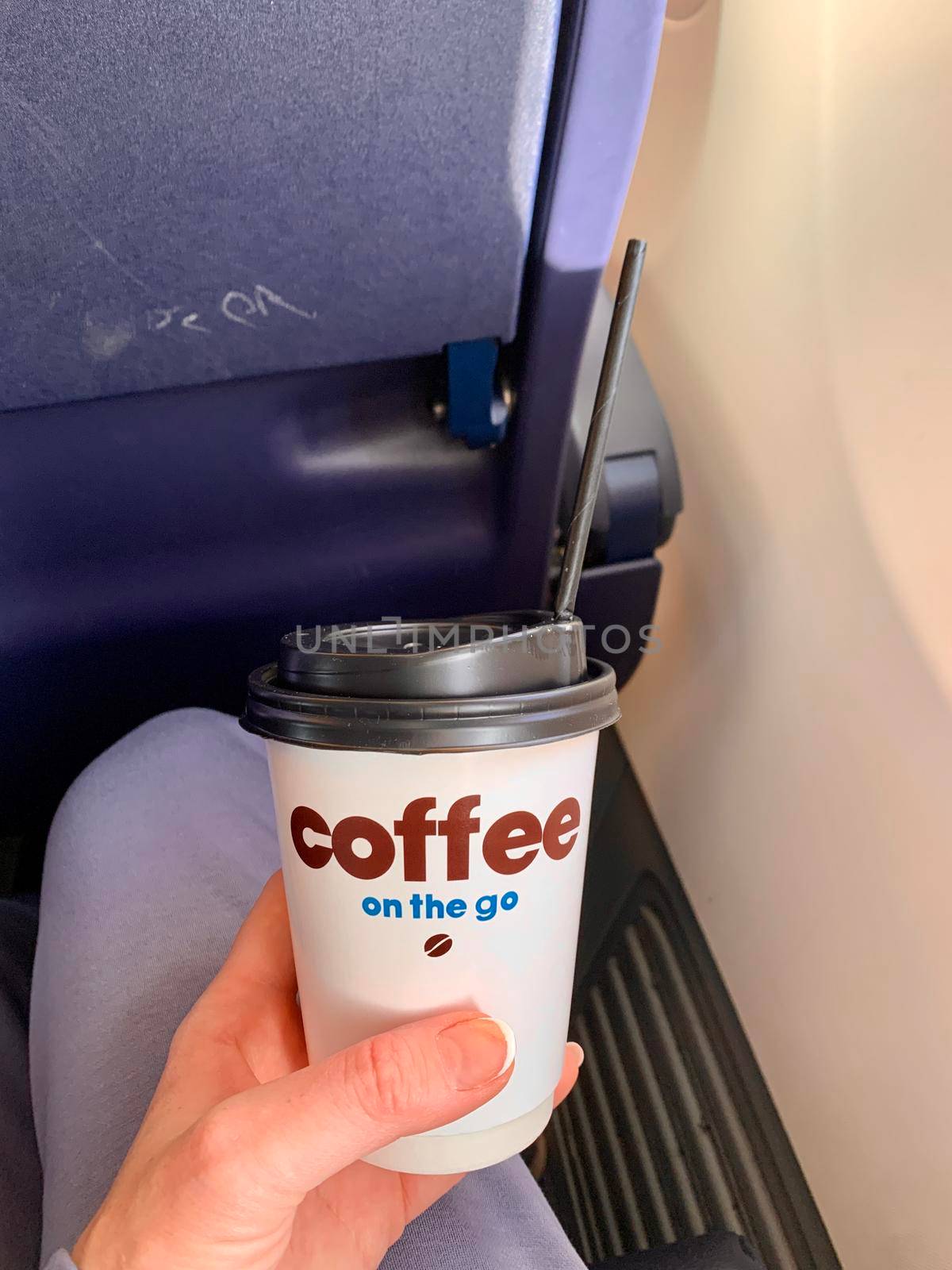 Woman drinking coffee on airplane.Woman hand holding white paper cup of hot coffee on the airplane. by juliet_summertime