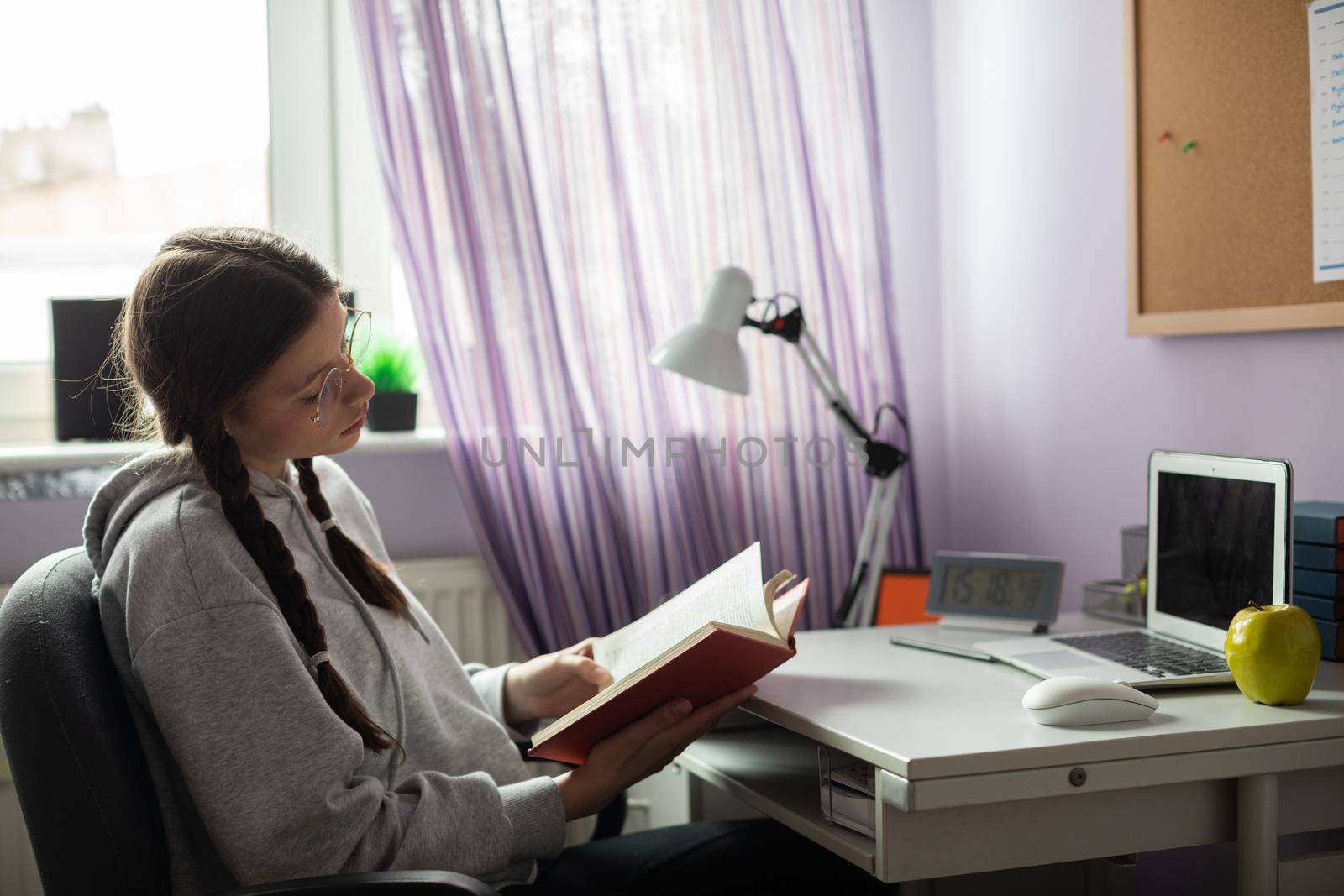 A young girl reads a school book. Gaining knowledge through school reading. A capable student. A young girl with braids.