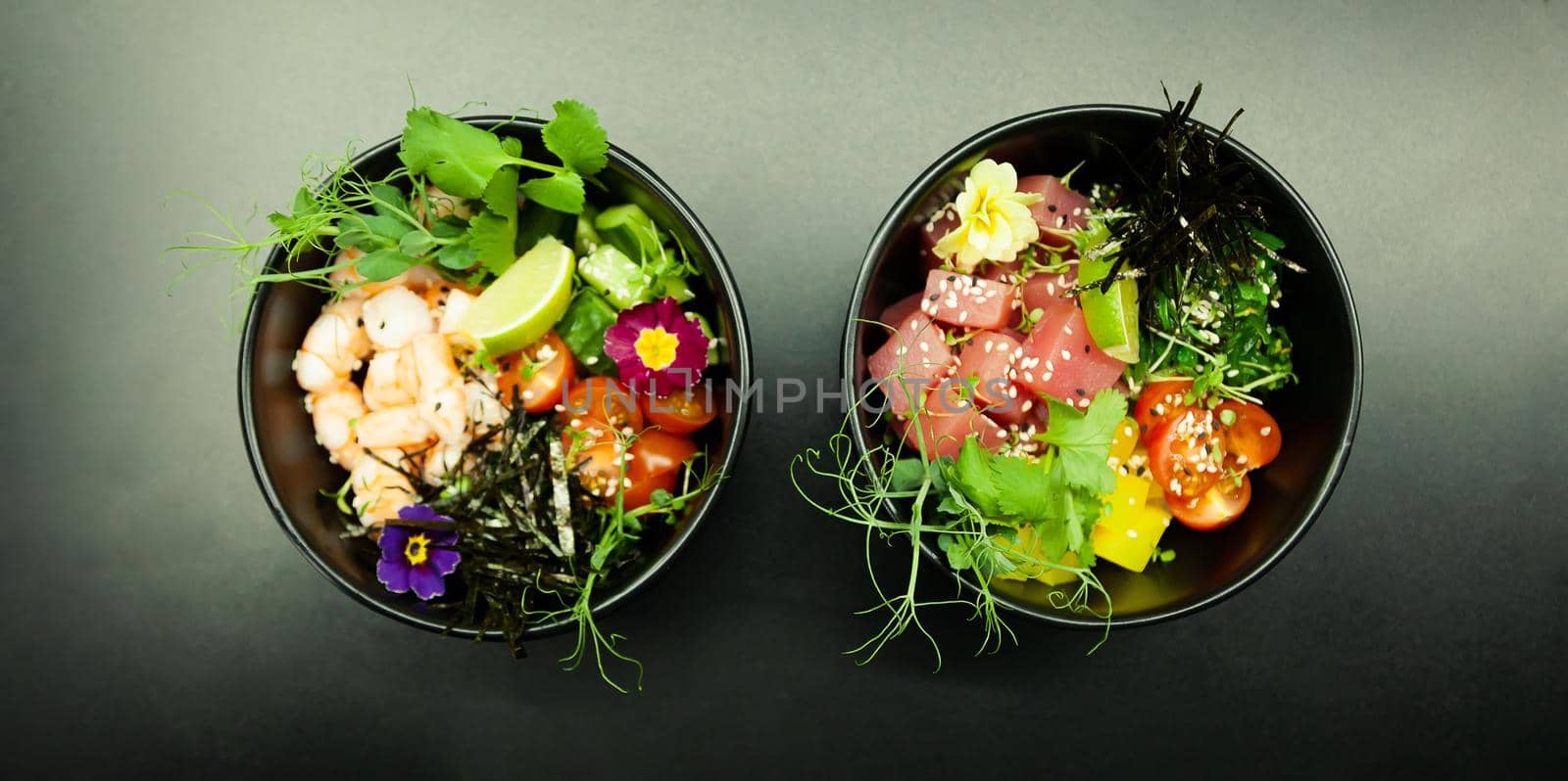 Poke salads with tuna and beef in bowls on the table. Two bowls of poke salad with chopsticks on a gray background. Asian seafood salad concept by ViShark