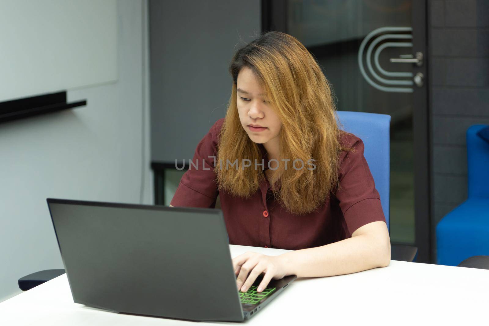 Asian woman is student,businesswoman working by computer notebook, laptop in office meeting room with whiteboard background with thinking, concentrate emotion in concept working woman,success in life