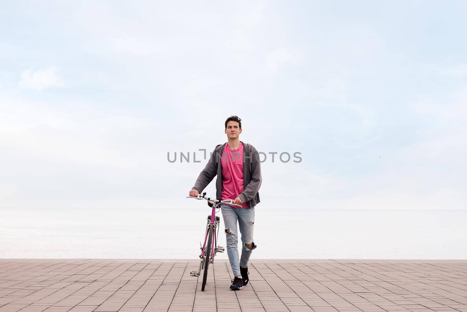 front view of a young student walking while pushing a bike, concept of ecological and sustainable transportation, copy space for text