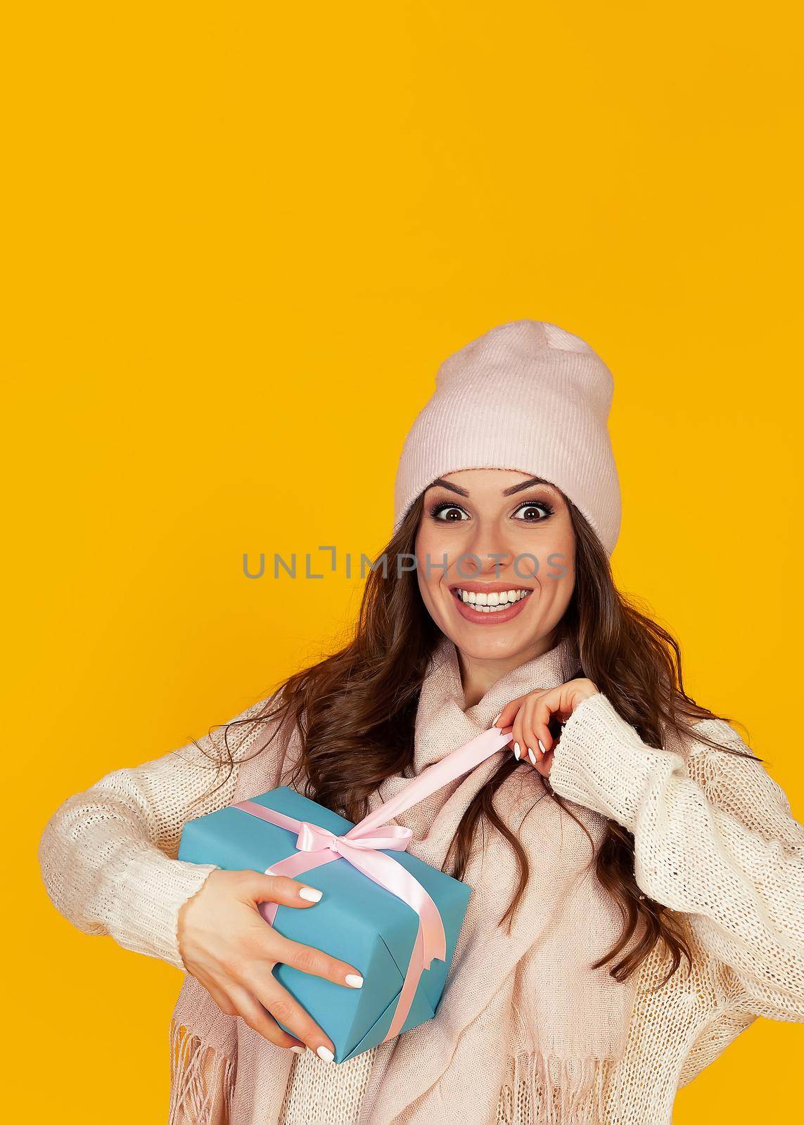 Happy young woman with open mouth opening a gift box of Christmas present, Girl looks into the gift box and laughs with happiness. The concept of gifts and surprises for the new year and christmas