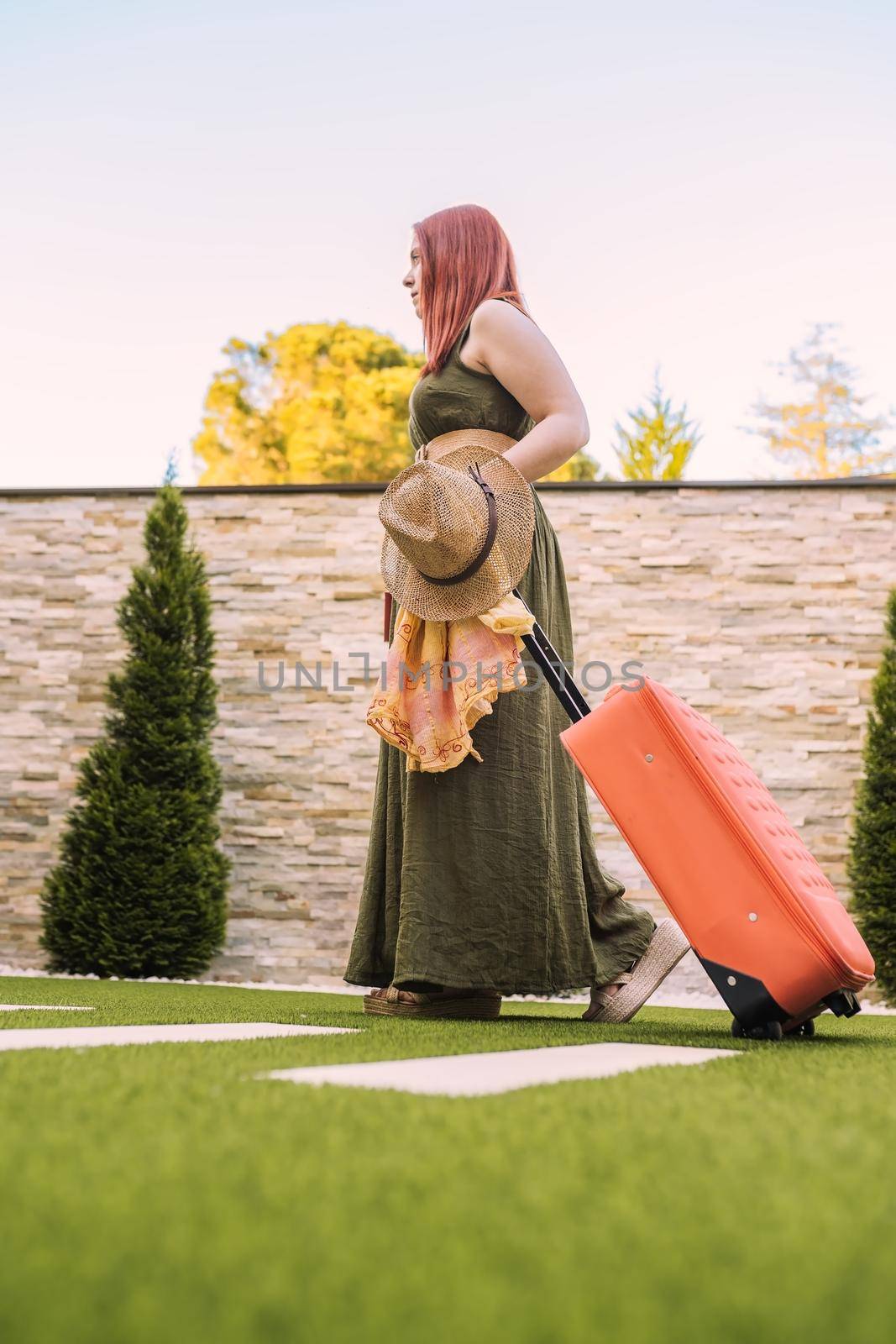 young woman traveller, entering hotel reception with her wheeled suitcase. woman on recreational trip. concept of rest and holiday. by CatPhotography