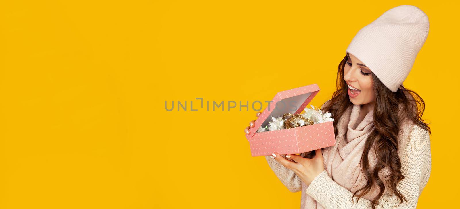 Happy young woman with open mouth opening a gift box of Christmas present, Girl looks into the gift box and laughs with happiness. The concept of gifts and surprises for the new year and christmas