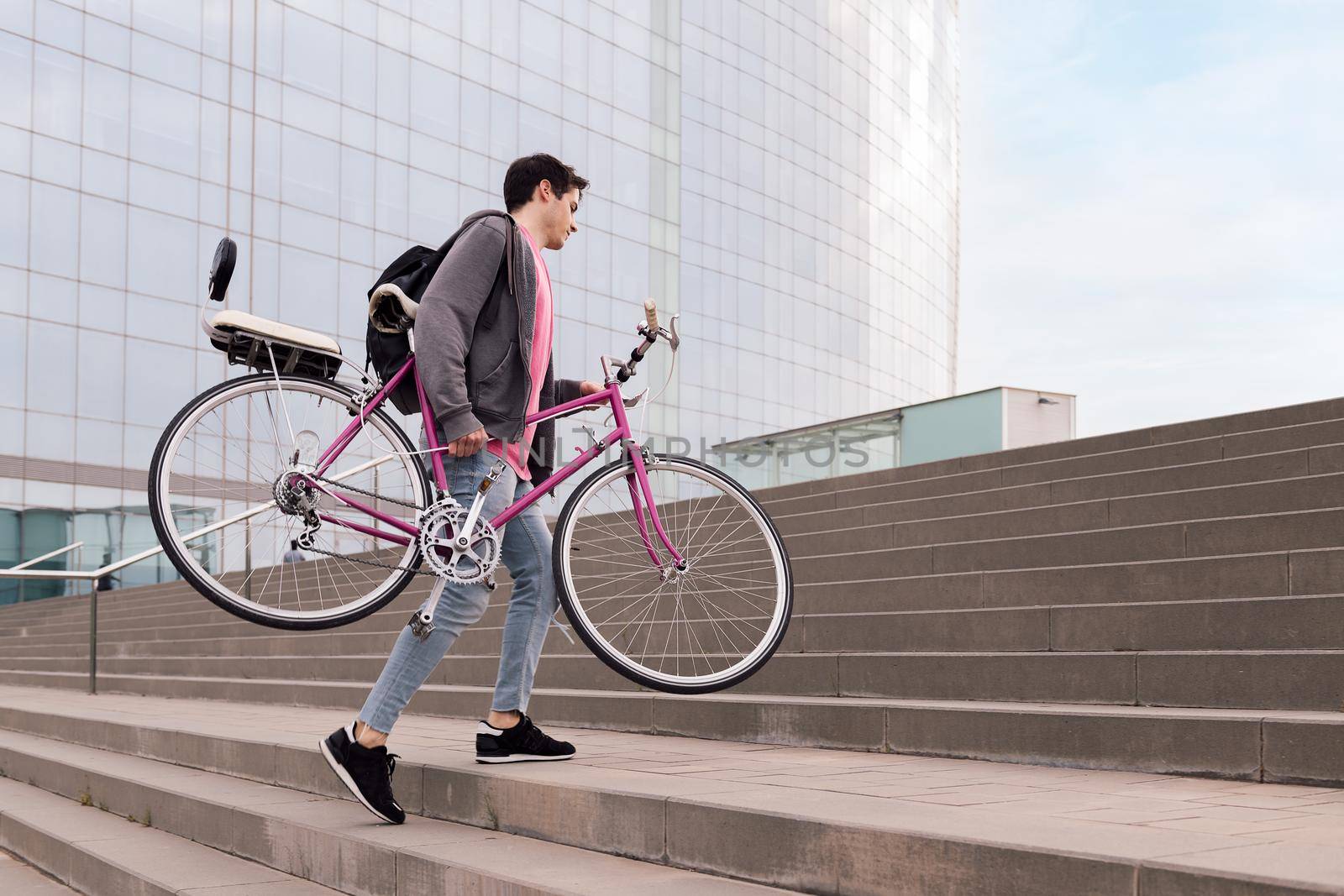 young man carrying bicycle up the stairs, concept of sustainable urban transportation and ecological lifestyle, copy space for text