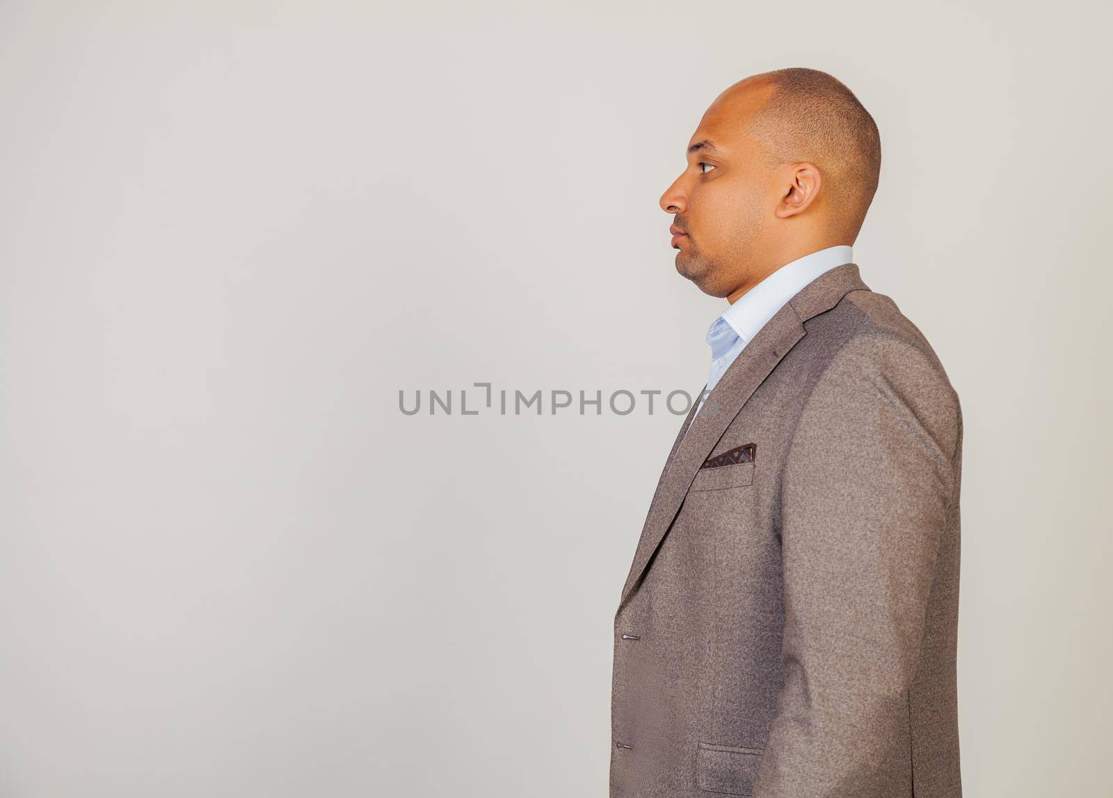 Young African American man standing looking to the side. Serious African man male, standing in profile, looking to the side, posing for a photo. Confident black guy looking forward to copy space by ViShark