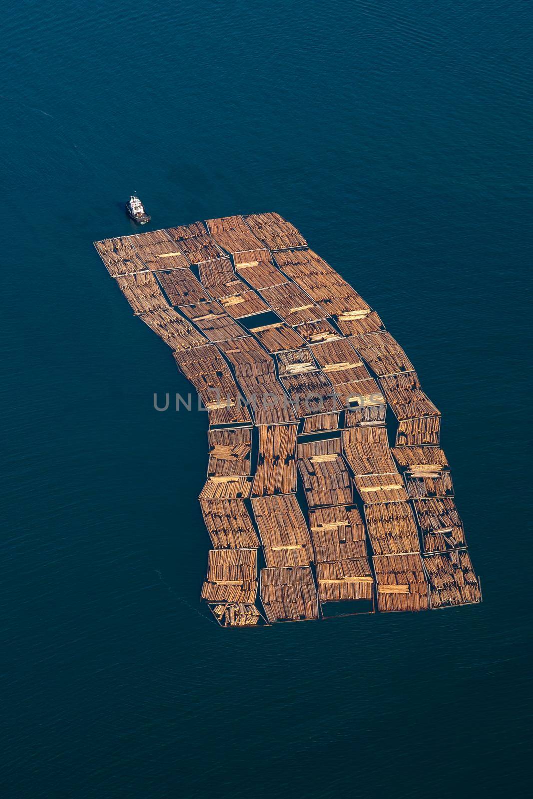 Tug boat pulling lumber wood in the ocean. Taken from aerial perspective near Sunshine Coast, British Columbia, Canada.