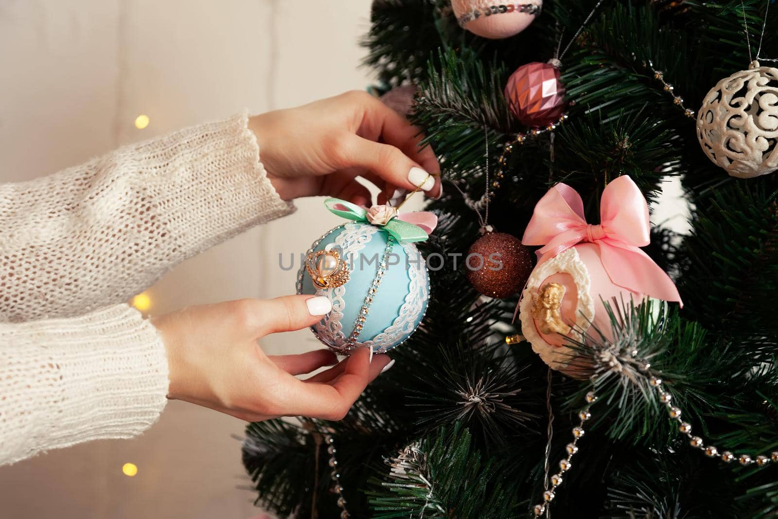 Close-up of female hands hang the ball on the tree. Christmas decoration, toys hanging on the tree, Christmas tree ball. New year and christmas holiday concept
