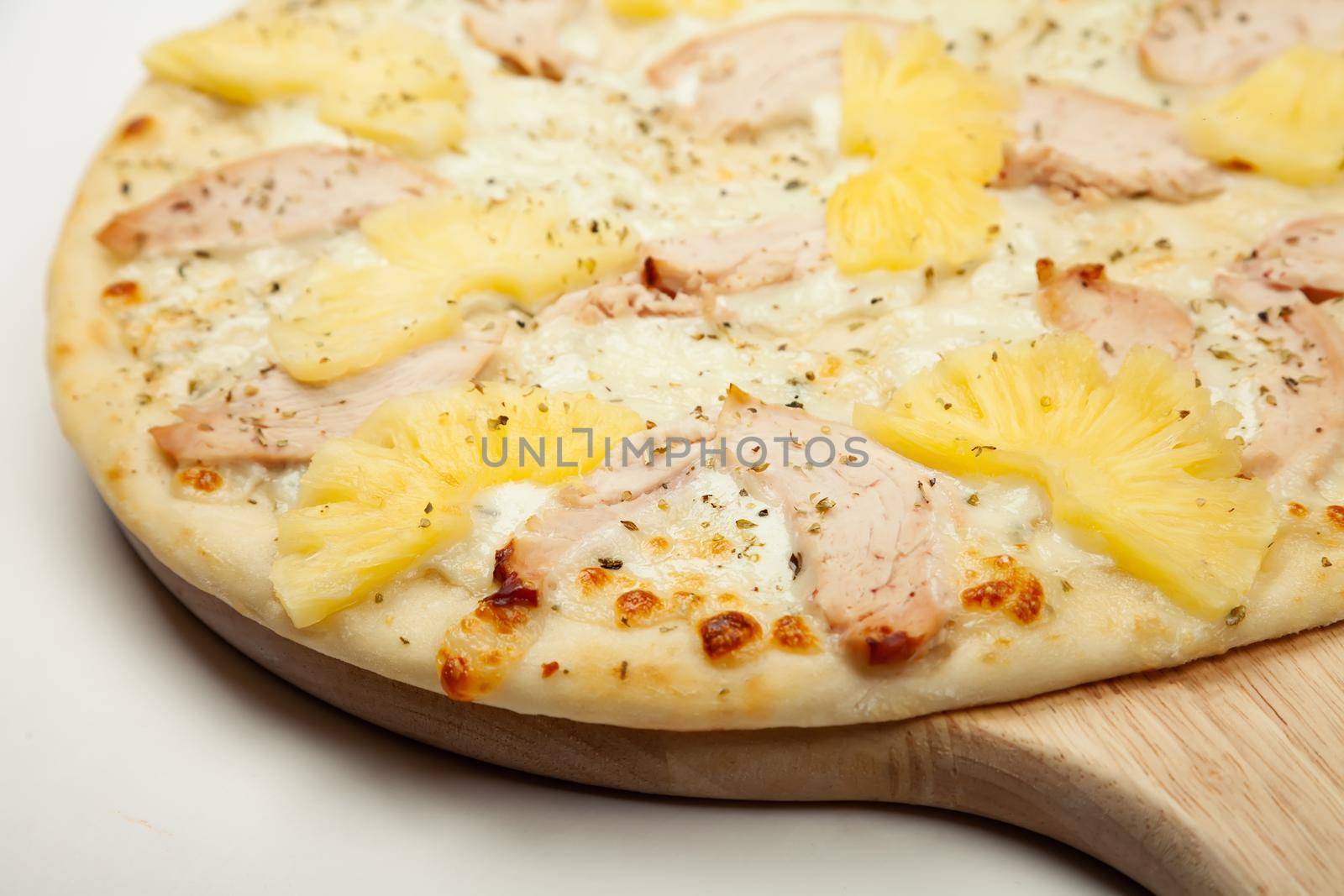 Texture Delicious Hawaiian pizza served on a wooden plate, ingredients garlic sauce, mozzarella cheese, smoked chicken, canned pineapples on white. Pizzeria promotion poster.