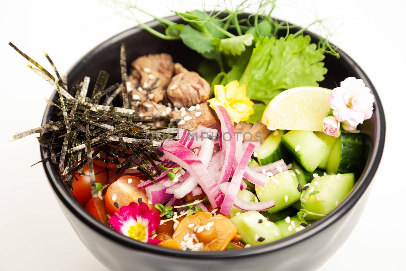 Poke salad with beef in a bowl. Ingredients Beef, Nameko mushrooms, cherry tomatoes, rice, cucumber, red onion, Kim Chi sauce, Ponzu sauce, nori, sesame seeds, cilantro, lime. Asian salad concept.