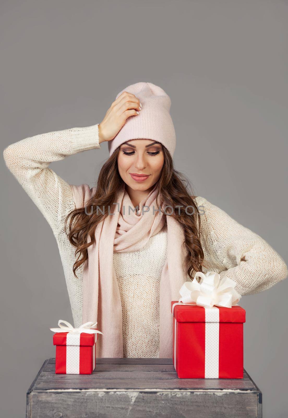 A beautiful young woman cannot decide which gift to choose, looks at a small and large box. The girl makes Christmas shopping, meets the New Year. Shopping sale concept